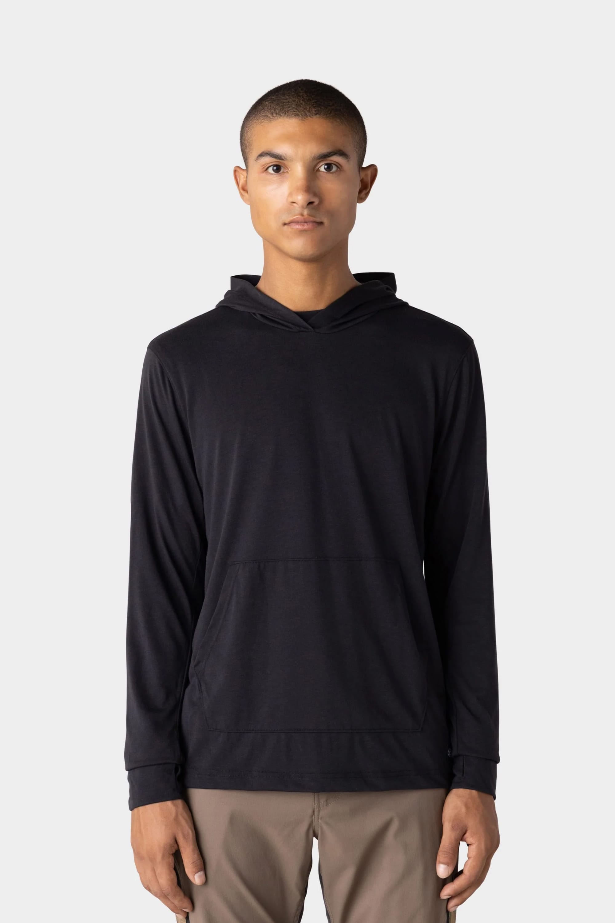 A person stands facing forward against a plain light gray background, wearing the 686 Mens Everywhere drirelease® Long Sleeve Hooded Tech Tee in black.