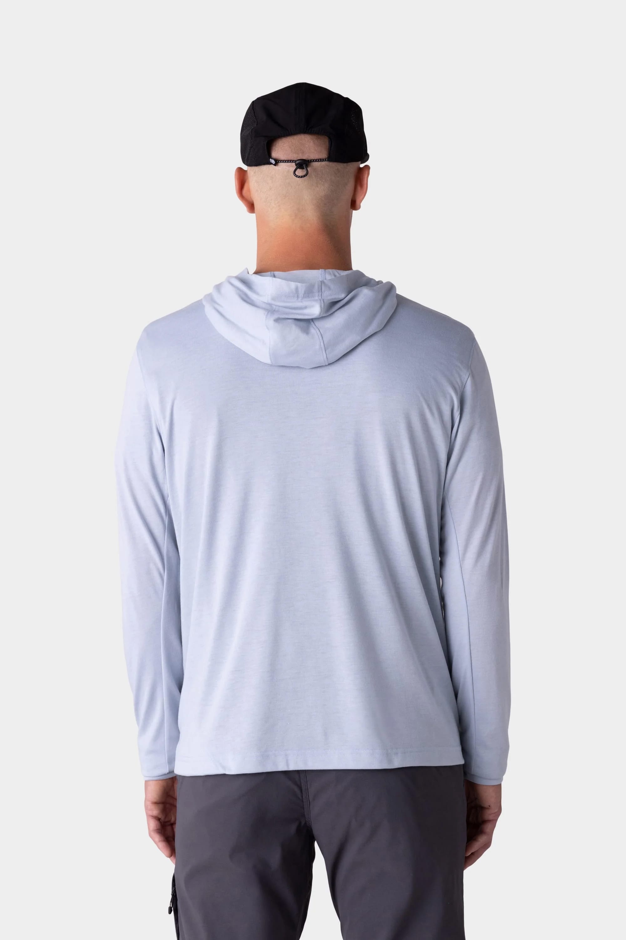 A person is shown from the back against a plain white background, wearing the 686 Mens Everywhere drirelease® Long Sleeve Hooded Tech Tee in light gray and a black cap.