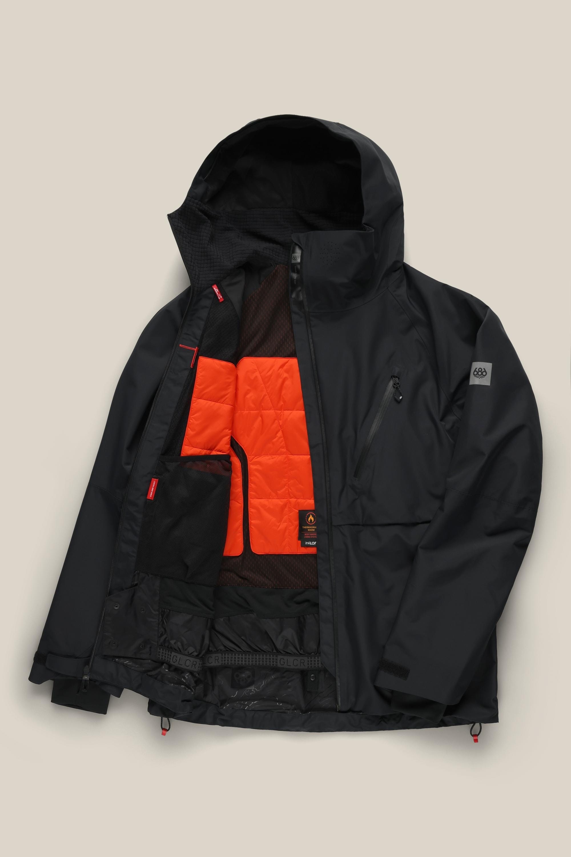 The 686 Men's Hydra™ Thermagraph® Jacket by 686 is displayed open on a beige background, revealing its bright orange body-mapped lining and inner mesh pockets.