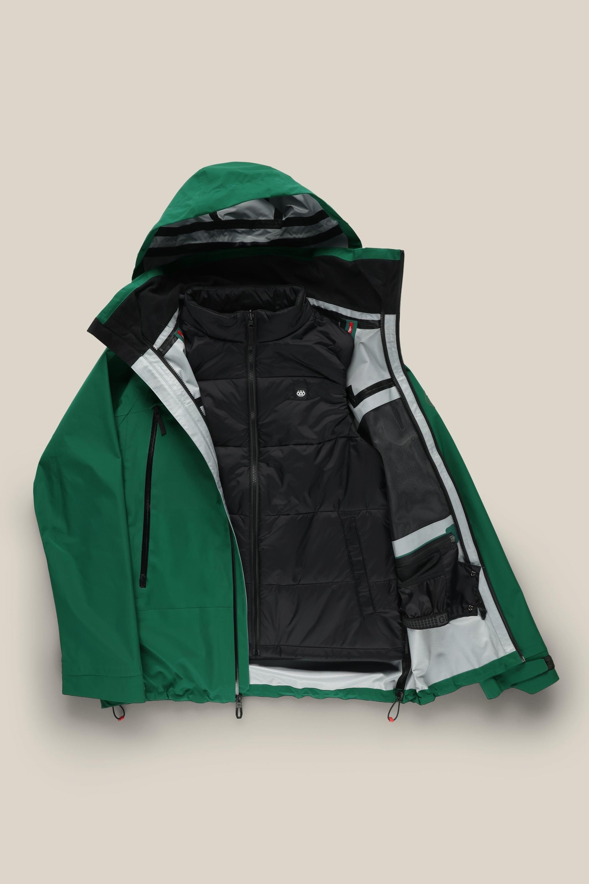 The 686 Men's SMARTY® 3-In-1 Rodeo™ 3L Jacket is displayed unzipped on a beige background, showing its black inner lining with zippered pockets and mesh compartments.