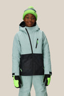 A smiling child wears the 686 Boys Hydra Insulated Jacket in mint green and black, with matching pants, a neon green and gray knit beanie, and neon green gloves, standing against a plain beige background.