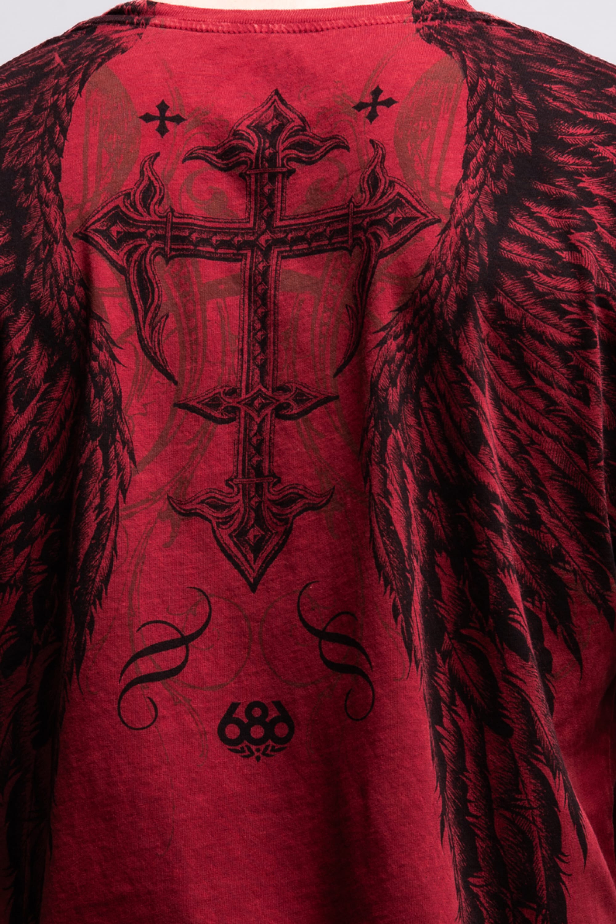 The 686 Affliction Death Eyes SS Tee by 686 is a bold red men’s t-shirt with a large black ornate cross, angel wings, swirling details, and the number 68 near the bottom. Made from 100% cotton for comfort and style.