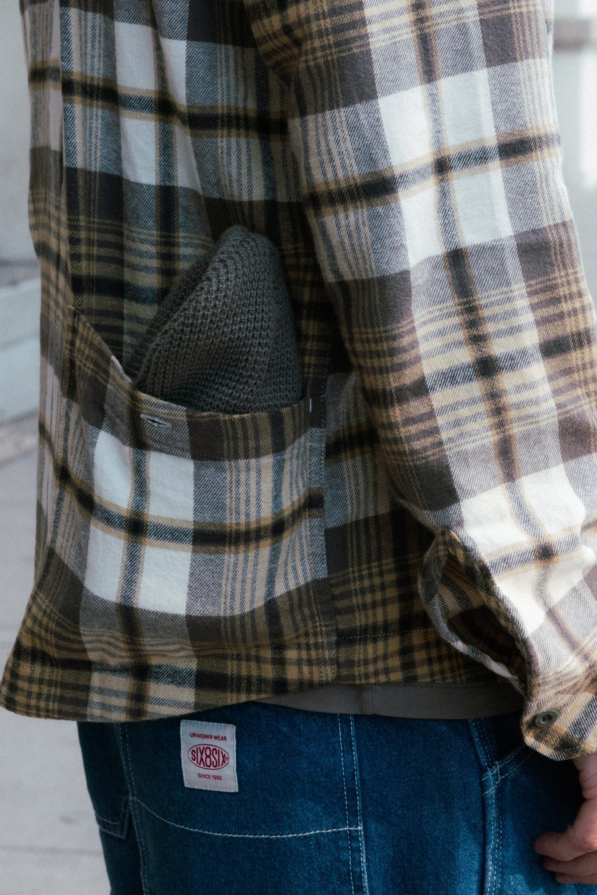 Close-up of a person wearing a brown and white 686 Men’s SMARTY® Headwall Flannel, with a knit beanie tucked into the chest pocket.