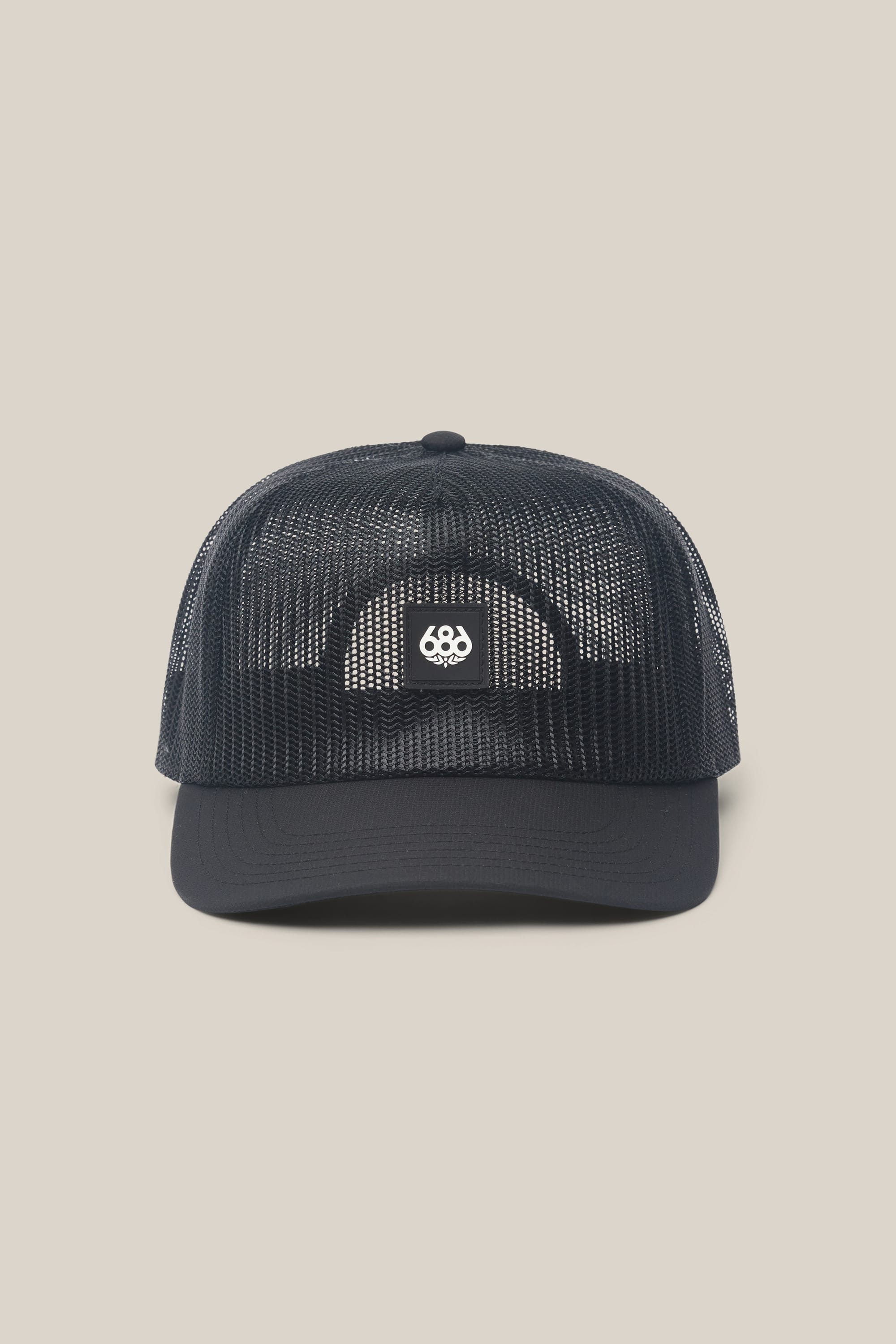 The 686 High-Pro Knockout Structured 5 Panel Hat by 686 is a black mesh trucker hat with a curved bill, shown from the front. Its front panel showcases a small, white circular logo featuring three interlocking number 6s. Stylish and modern, this men’s hat stands out against the solid light beige background.