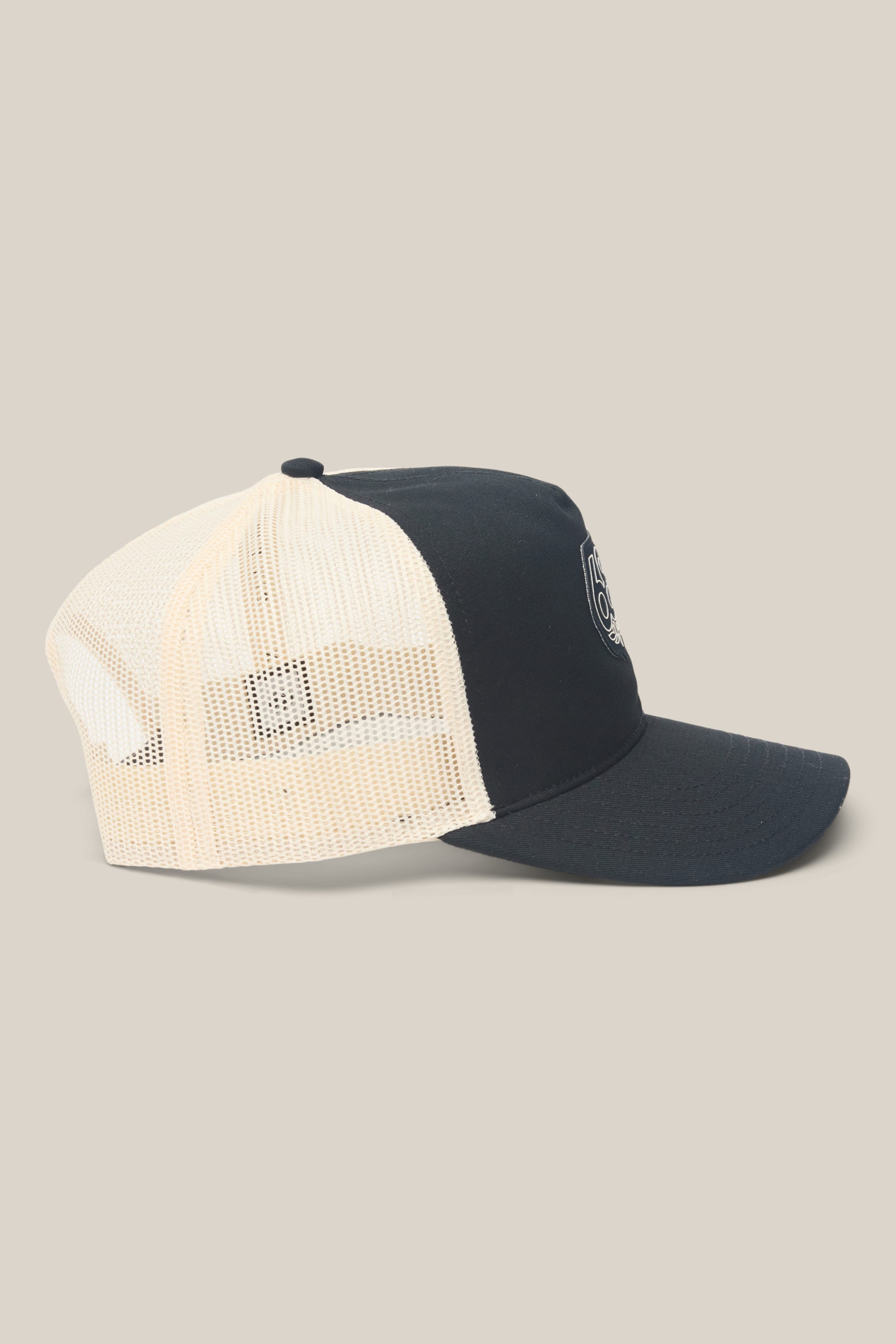 The 686 Mid-Pro Wreath Unstructured 5 Panel Mesh Hat by 686 is a black and white trucker hat with a curved bill, black front panel, and small round embroidered logo—crafted from durable polyester cotton. Shown in profile on beige background.
