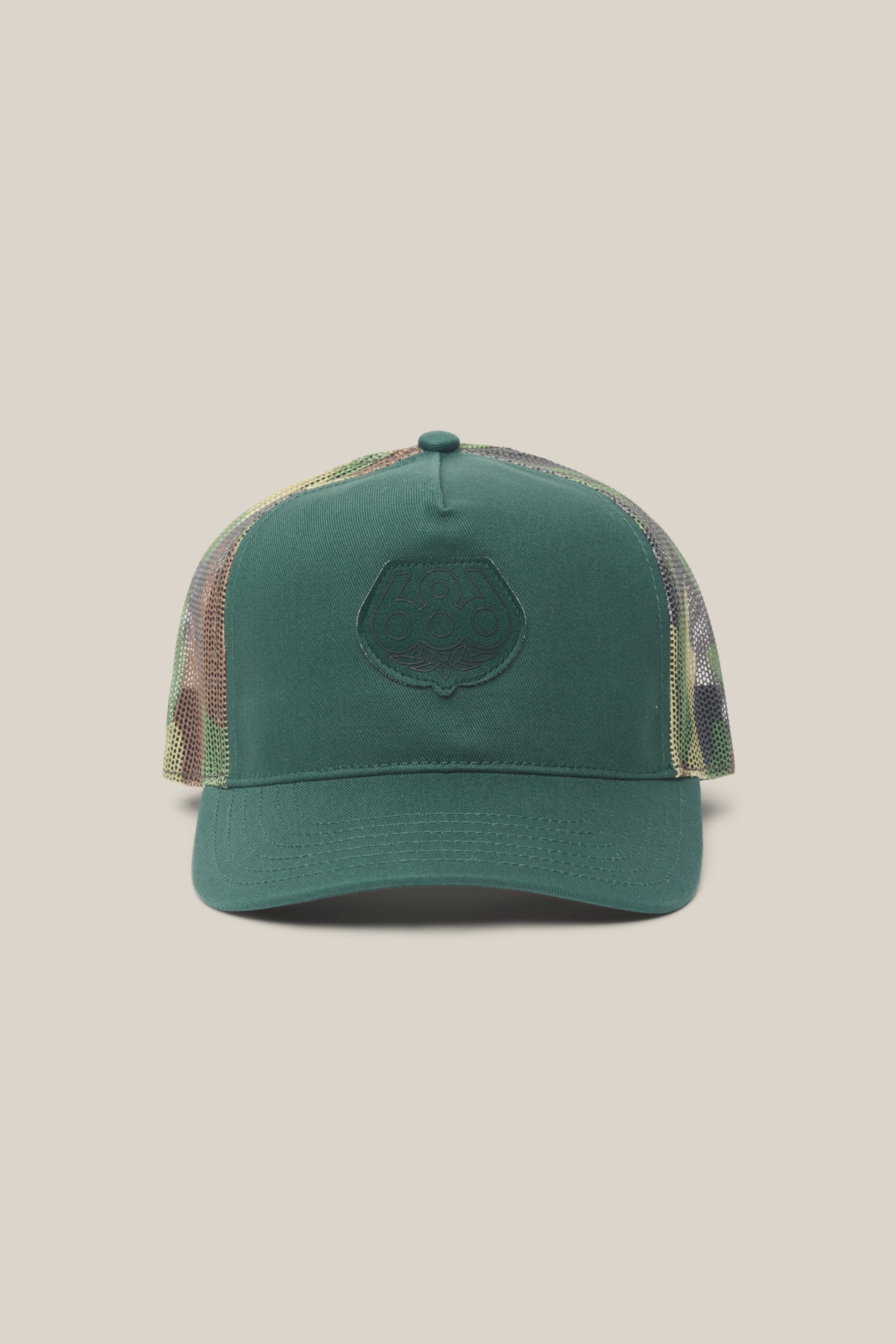 The 686 Mid-Pro Wreath Unstructured 5 Panel Mesh Hat by 686 features a green woven design with a mesh back, camouflage sides, and an embossed logo patch on the front panel. Its polyester-cotton build stands out against a light beige background.