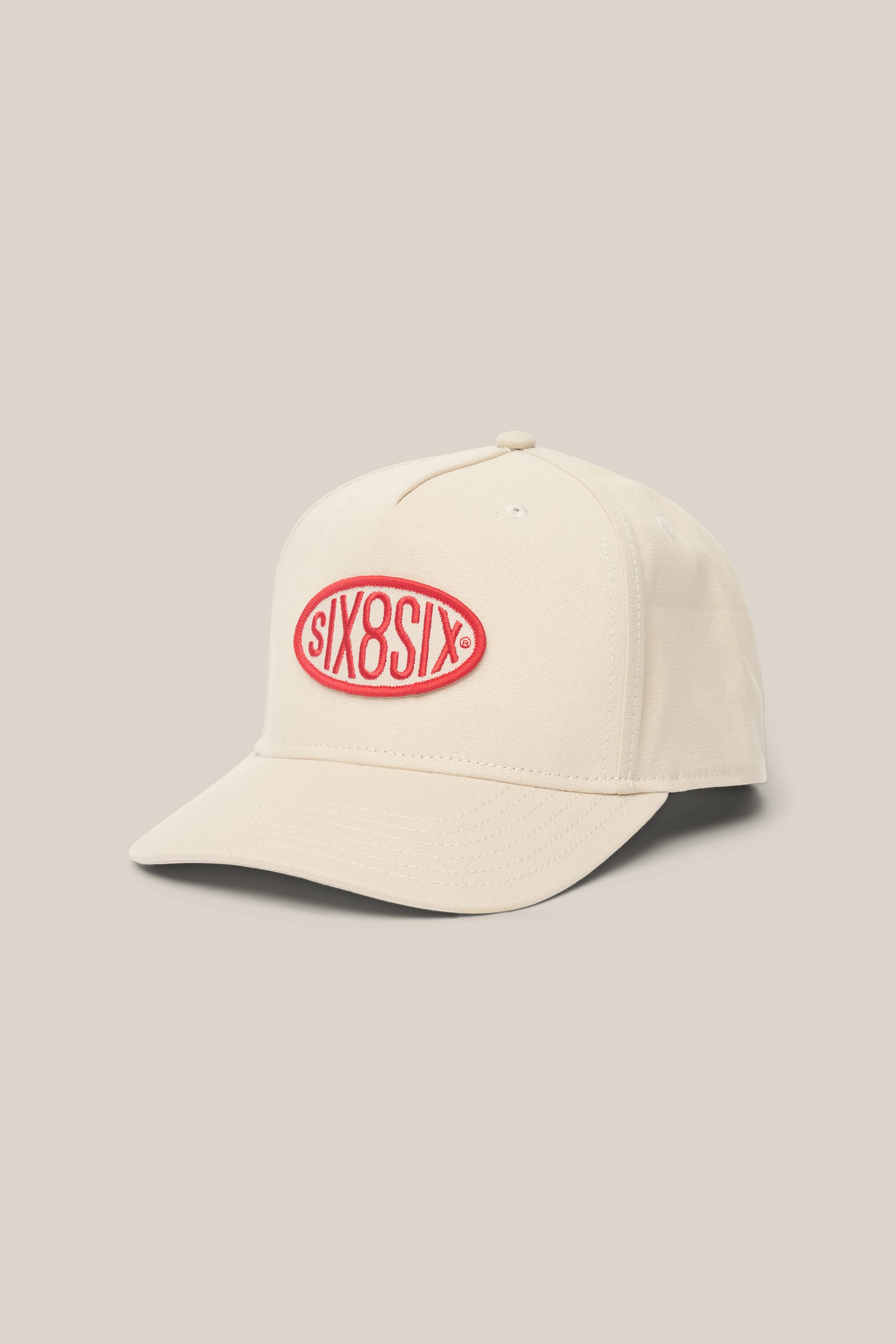The 686 High-Pro 92 Structured 5 Panel Hat by 686 is a beige men's polyester hat with a curved brim and a red oval patch on the front, showing "SIX8SIX" in white lettering. The background matches the beige color of the hat.