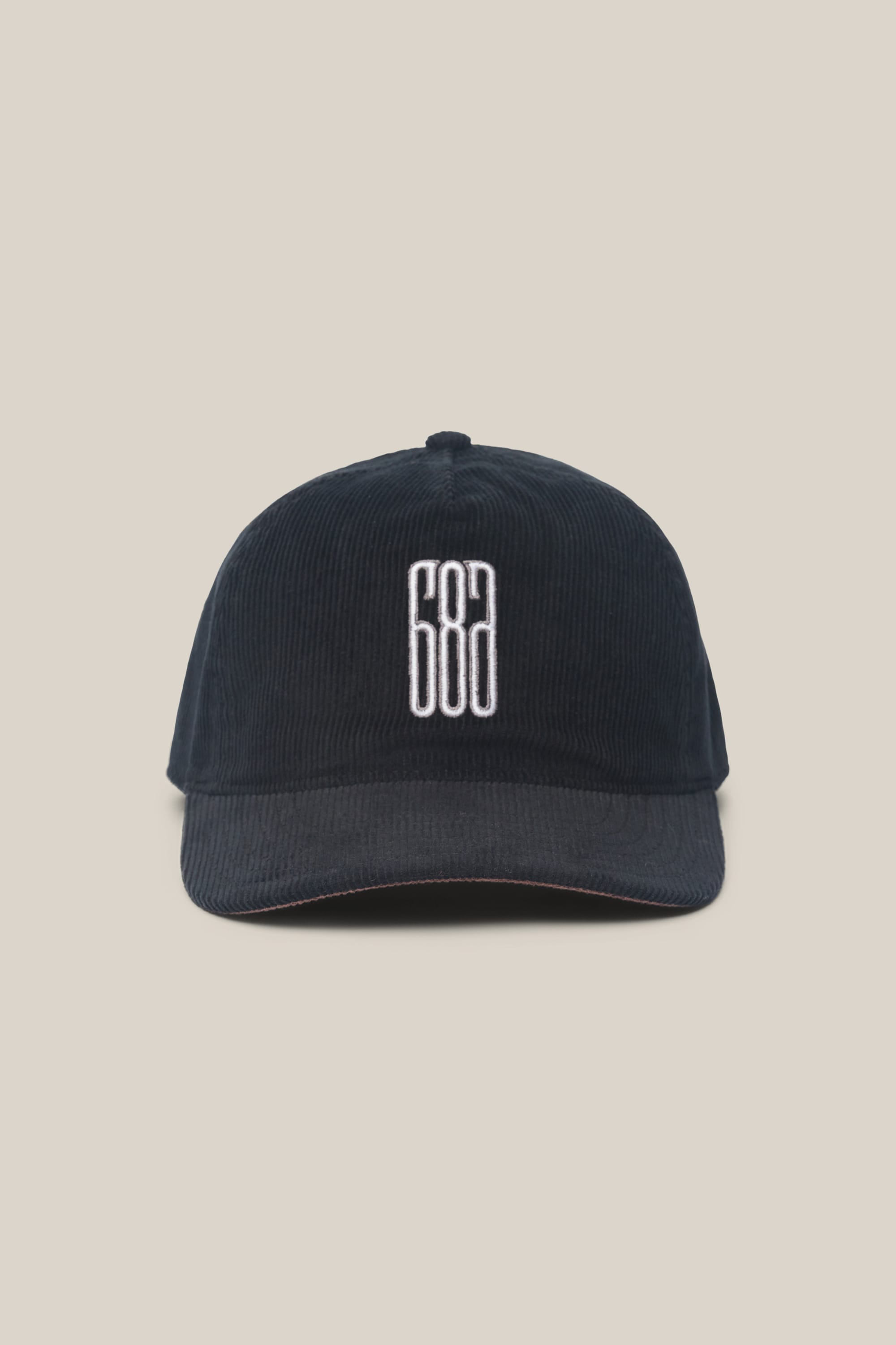 The 686 Mid-Pro Ghost Cord Unstructured 5 Panel Hat by 686 is a black corduroy baseball cap, crafted from a polyester-cotton blend with woven construction. It features white geometric embroidered text on the front and is displayed against a plain beige background.