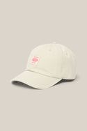 The 686 Low-Pro Unwork Unstructured 6 Panel Hat by 686 is a light beige men's woven hat with a curved brim and a small pink rectangular front patch featuring text, shown on a matching beige background.