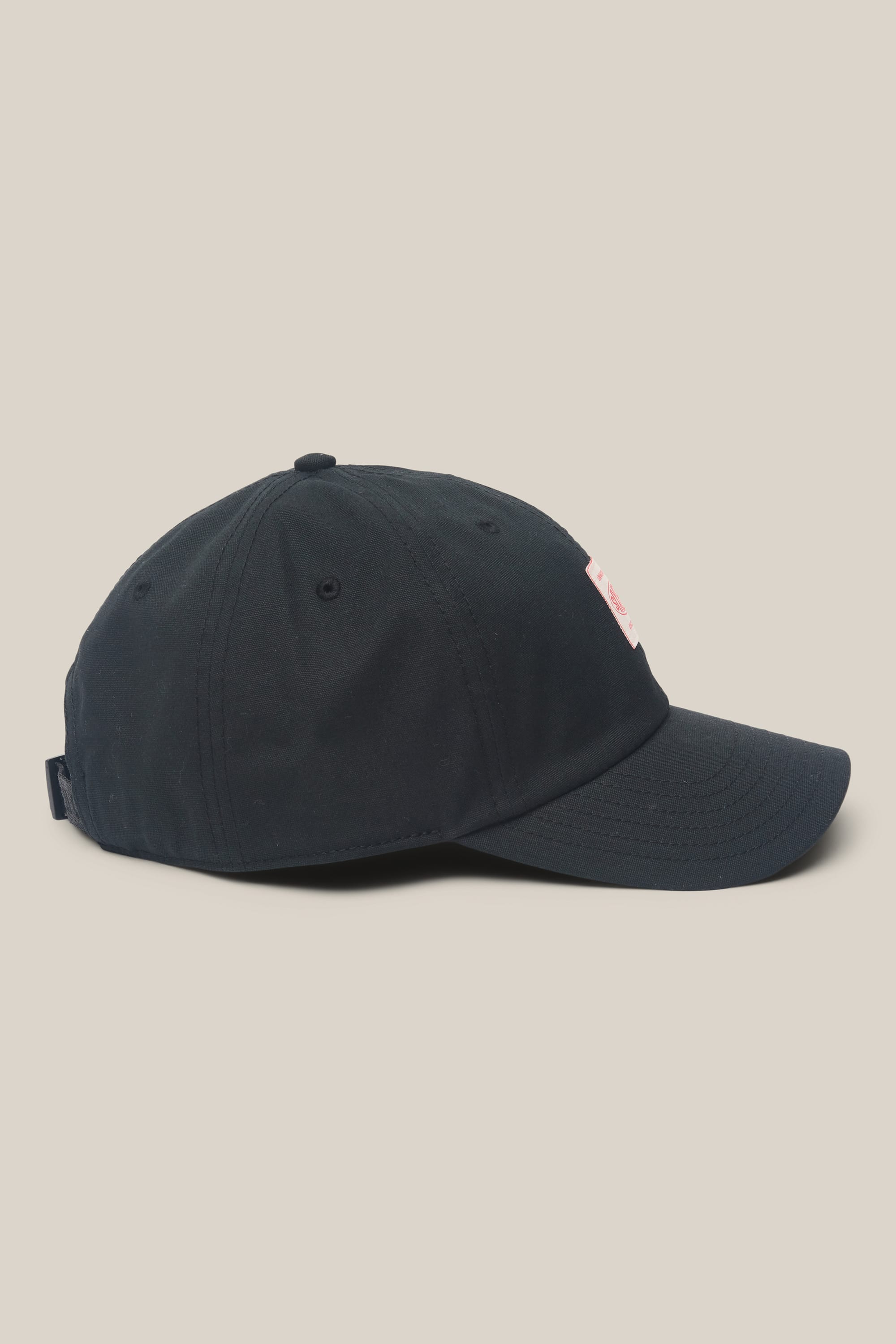 Introducing the 686 Low-Pro Unwork Unstructured 6 Panel Hat by 686—a sleek black baseball cap featuring a curved brim and a subtle rectangular white and red patch on the front. Crafted from a durable polyester-cotton blend for lasting comfort, this men’s hat is styled for everyday wear and showcased against a light beige background.