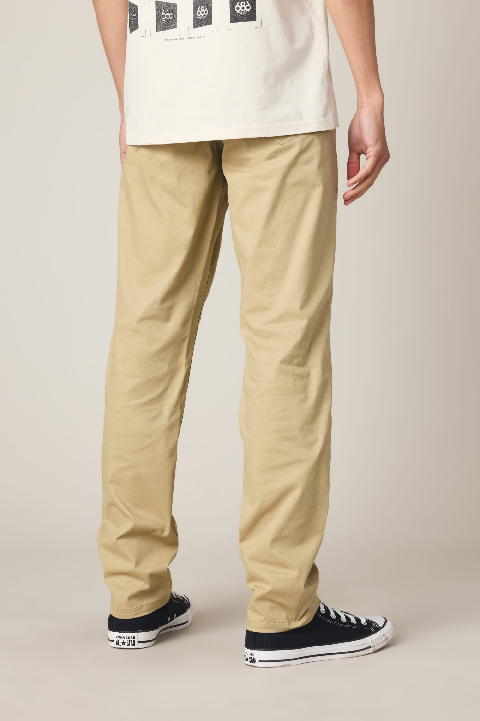 A person stands with their back to the camera, wearing 686 Men's Everywhere® Standard Pant - Slim Fit in khaki.