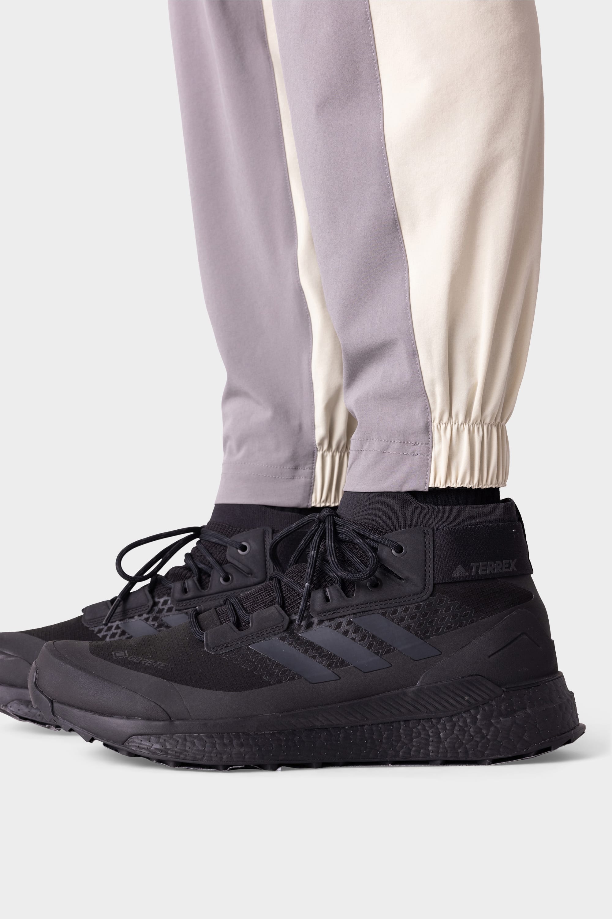 A person wearing black high-top sneakers and 686 Men's ATP Stretch Performance Pant by 686, standing on a white background.