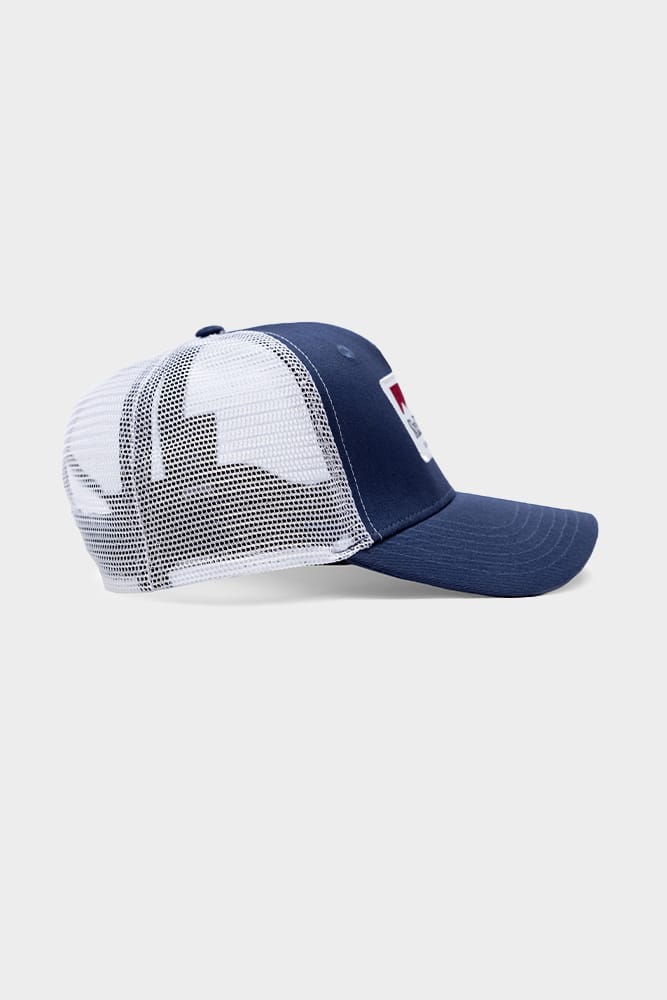 The 686 Trucker Hat by 686 features a solid blue front and brim with a white mesh back, displayed from the side on a light gray background.