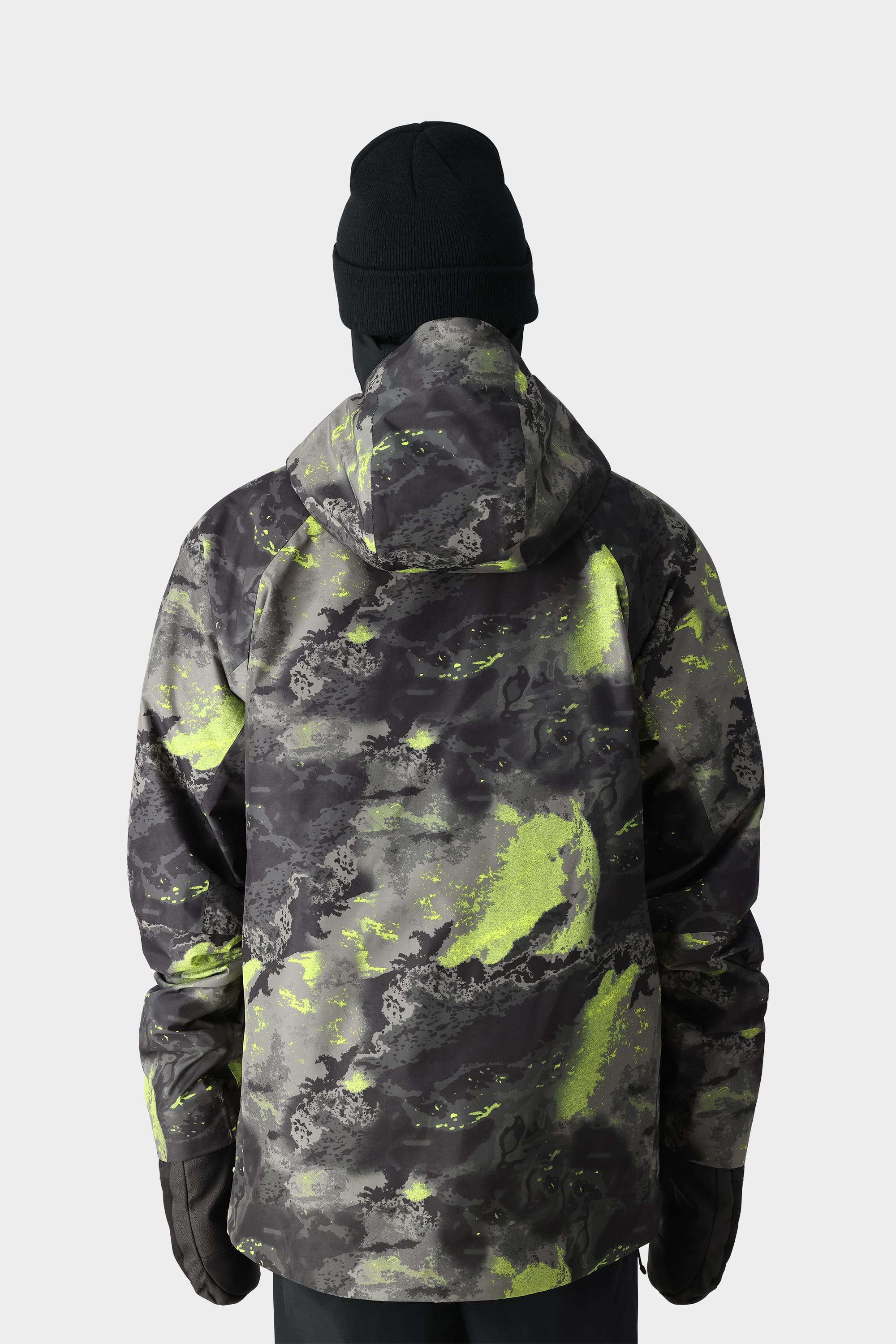A person in a black beanie and the 686 Men's GORE-TEX Hydra Down Thermagraph Jacket—with green and gray camouflage, body-mapped lining, and hood—faces away from the camera against a plain light background.