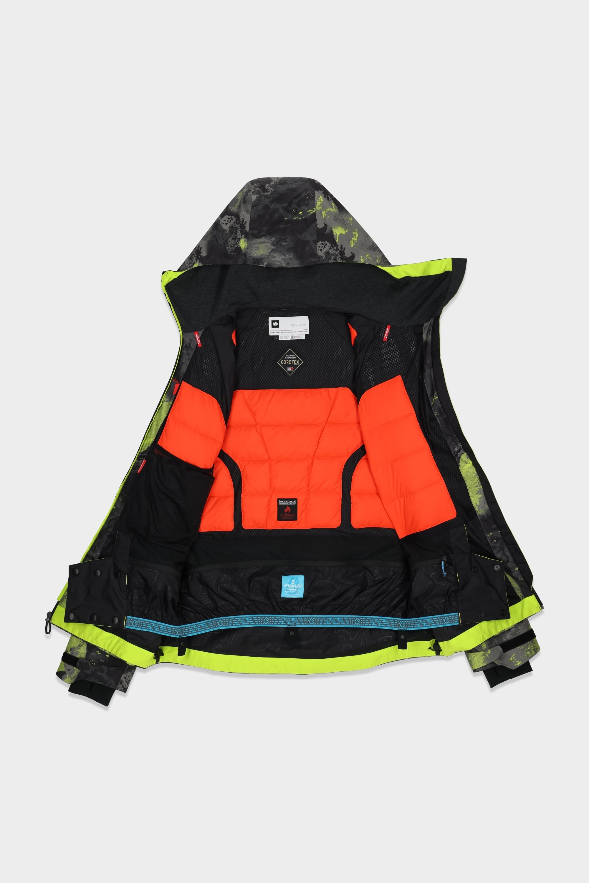 The 686 Men's GORE-TEX Hydra Down Thermagraph Jacket by 686 in black and green camo is laid flat, unzipped to show its bright orange and black padded lining with mesh pockets and inner labels.