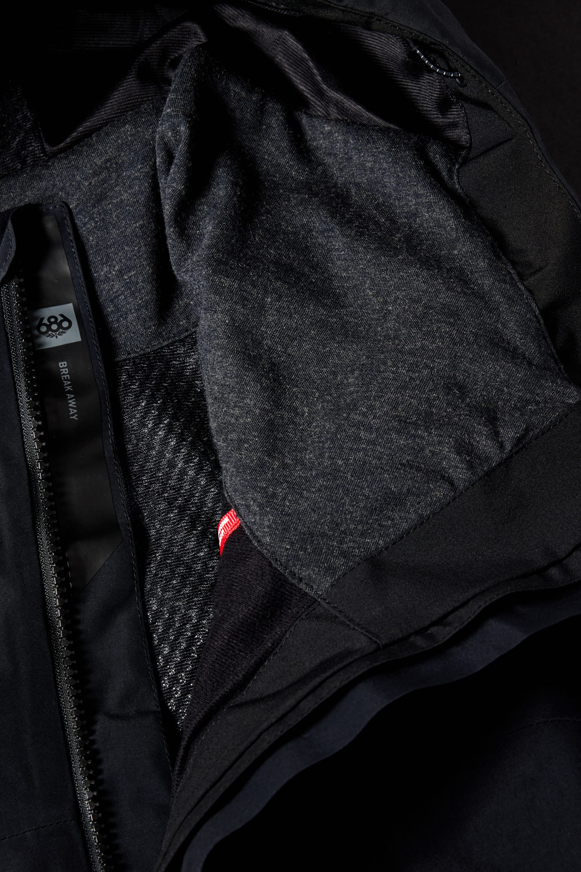 Close-up of the 686 Men's GORE-TEX Hydra Down Thermagraph Jacket shows body-mapped lining, grey interior, patterned black and grey section, a red tag, and visible labels with "686" and "SIX EIGHT SIX.