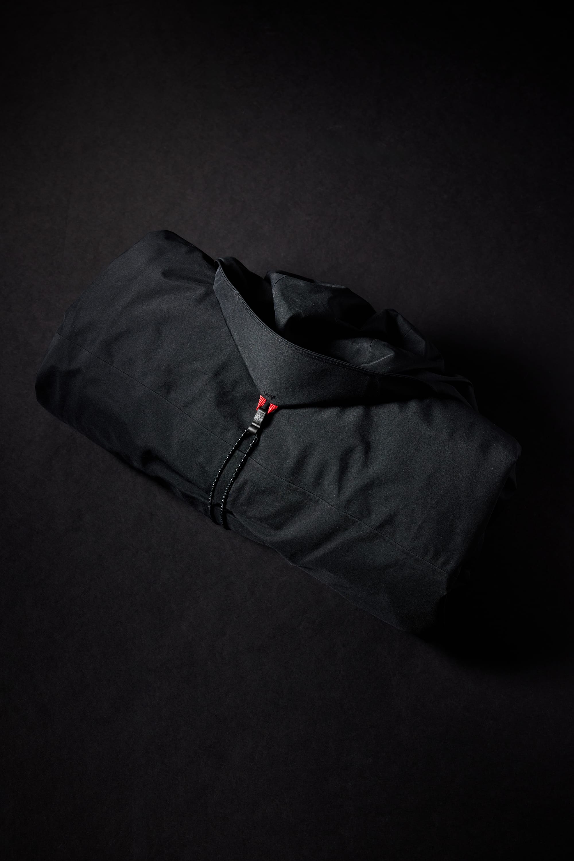 The 686 Men's GORE-TEX Hydra Down Thermagraph Jacket, a top seller from 686, is neatly folded on a dark surface. It features body-mapped lining and a subtle red accent near the zipper.
