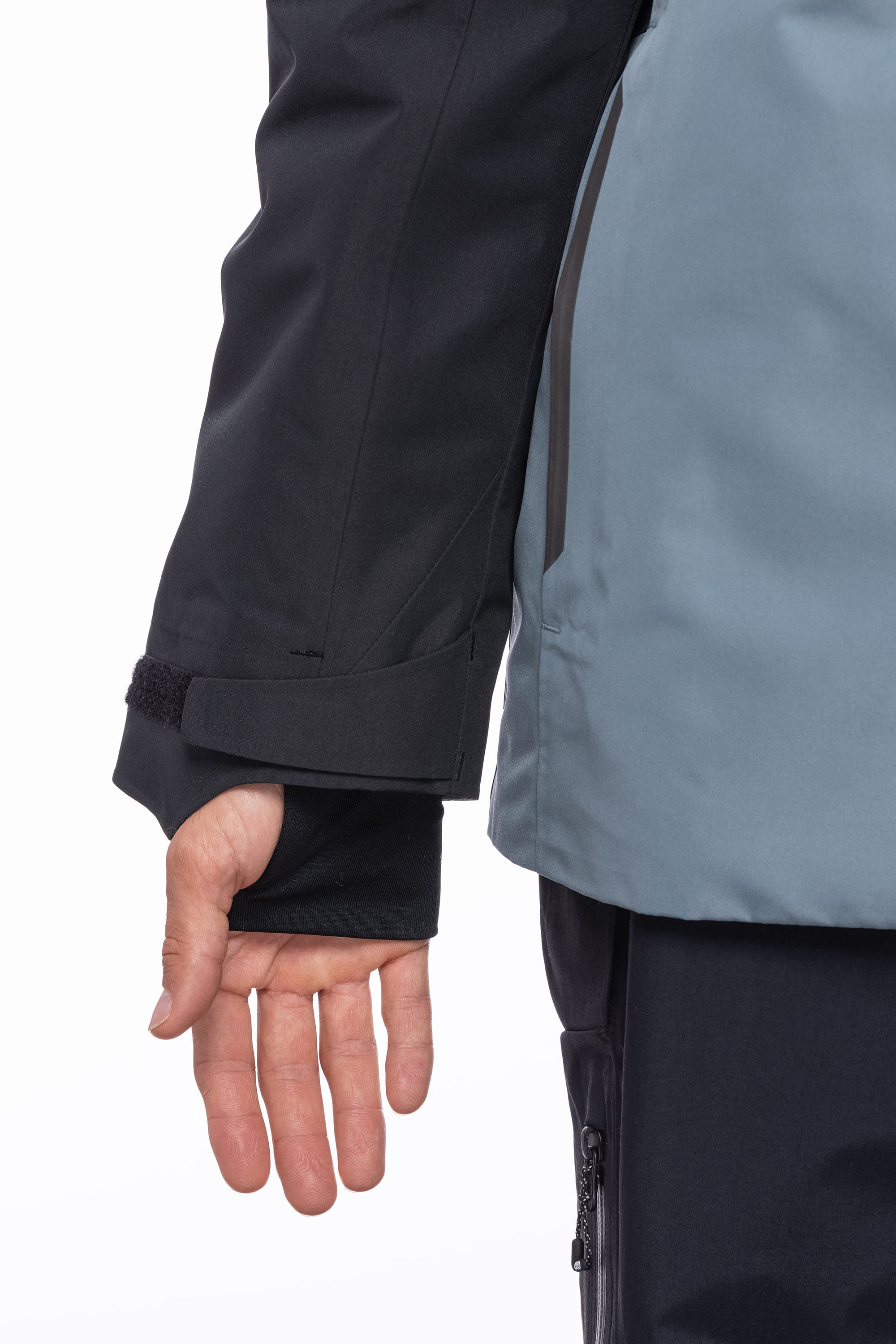 A close-up of a person’s left arm and hand wearing the 686 Men's Hydrastash Reserve Insulated Jacket in black and gray, with the polyester sleeve partially covering the hand and a black cuff at the wrist.