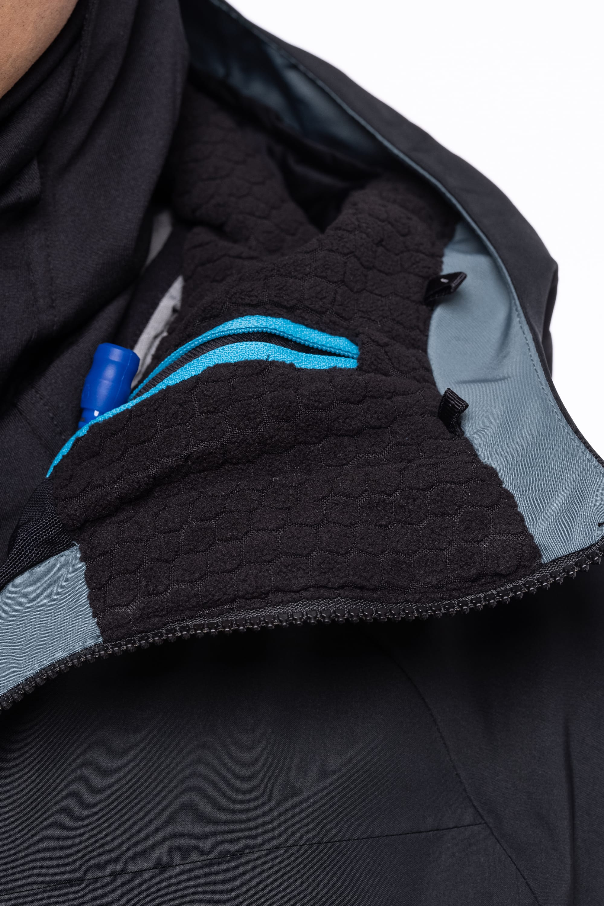 Close-up of the 686 Men's Hydrastash Reserve Insulated Jacket, partially unzipped to show its textured lining, a blue zipper, and a blue pen in the inner pocket.
