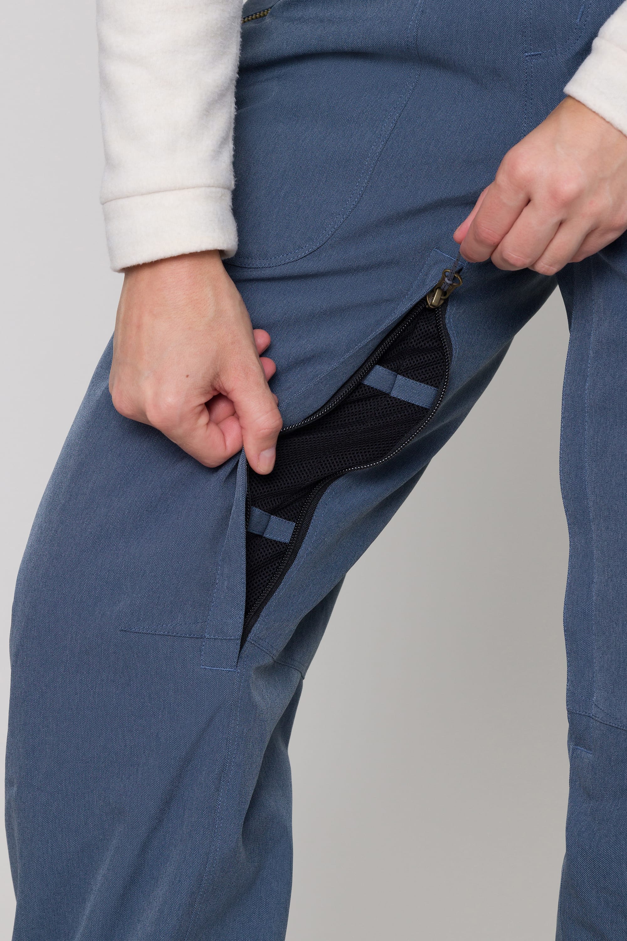 A person wearing the 686 Womens Black Magic Insulated Bib unzips a mesh-lined vent on the side, revealing the black mesh interior.