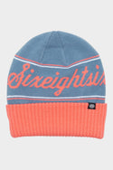 The 686 Girls Roll-Up Beanie features a blue knit design with a pink fold-over cuff, Sixeightsix in pink cursive on the front, and a small black logo tag on the cuff.