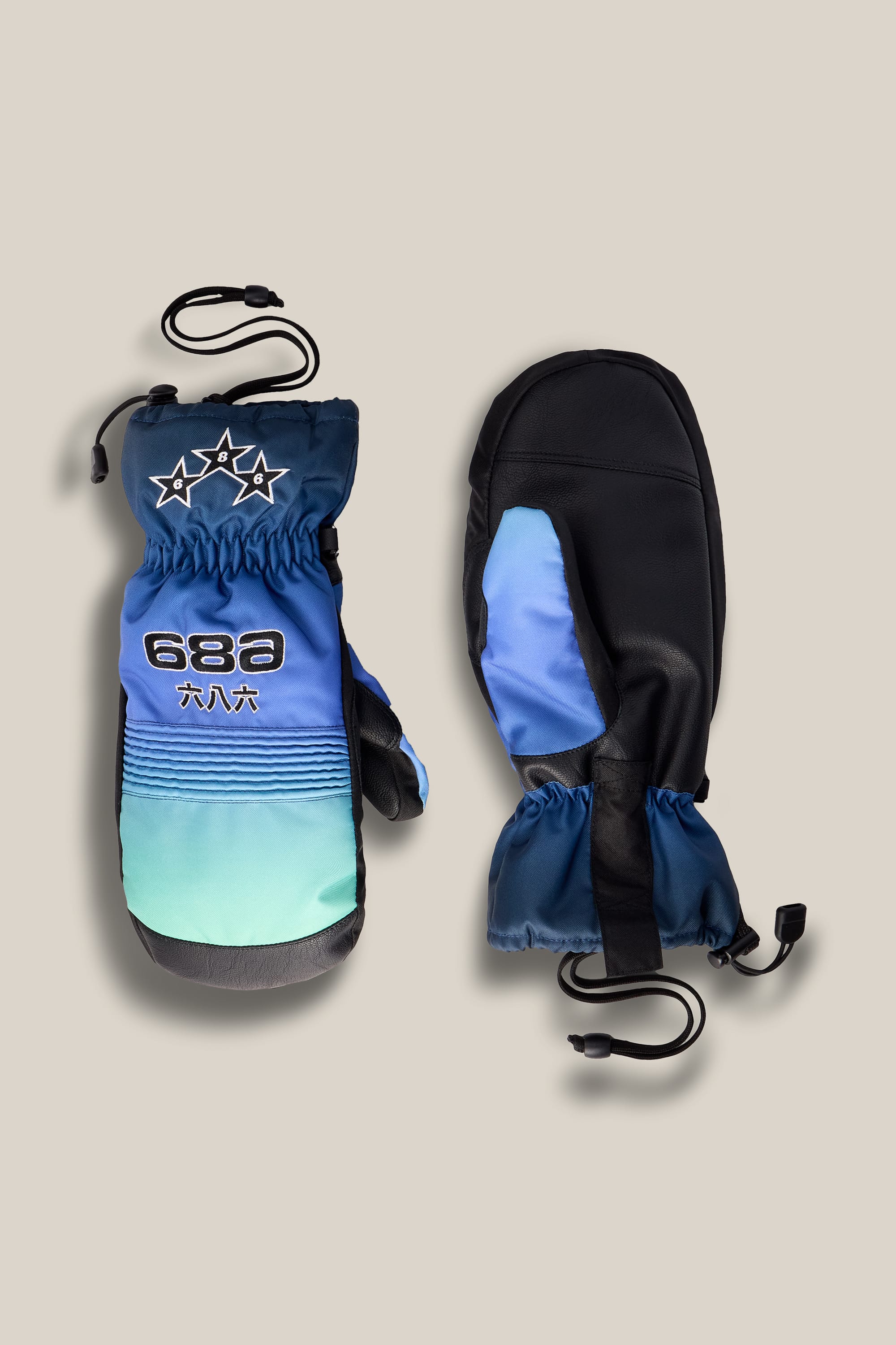 A pair of 686 Lander™ Mitts by 686, featuring blue, teal, and black colors with star designs, elastic wrists, and wrist cords, displayed flat on a beige background.