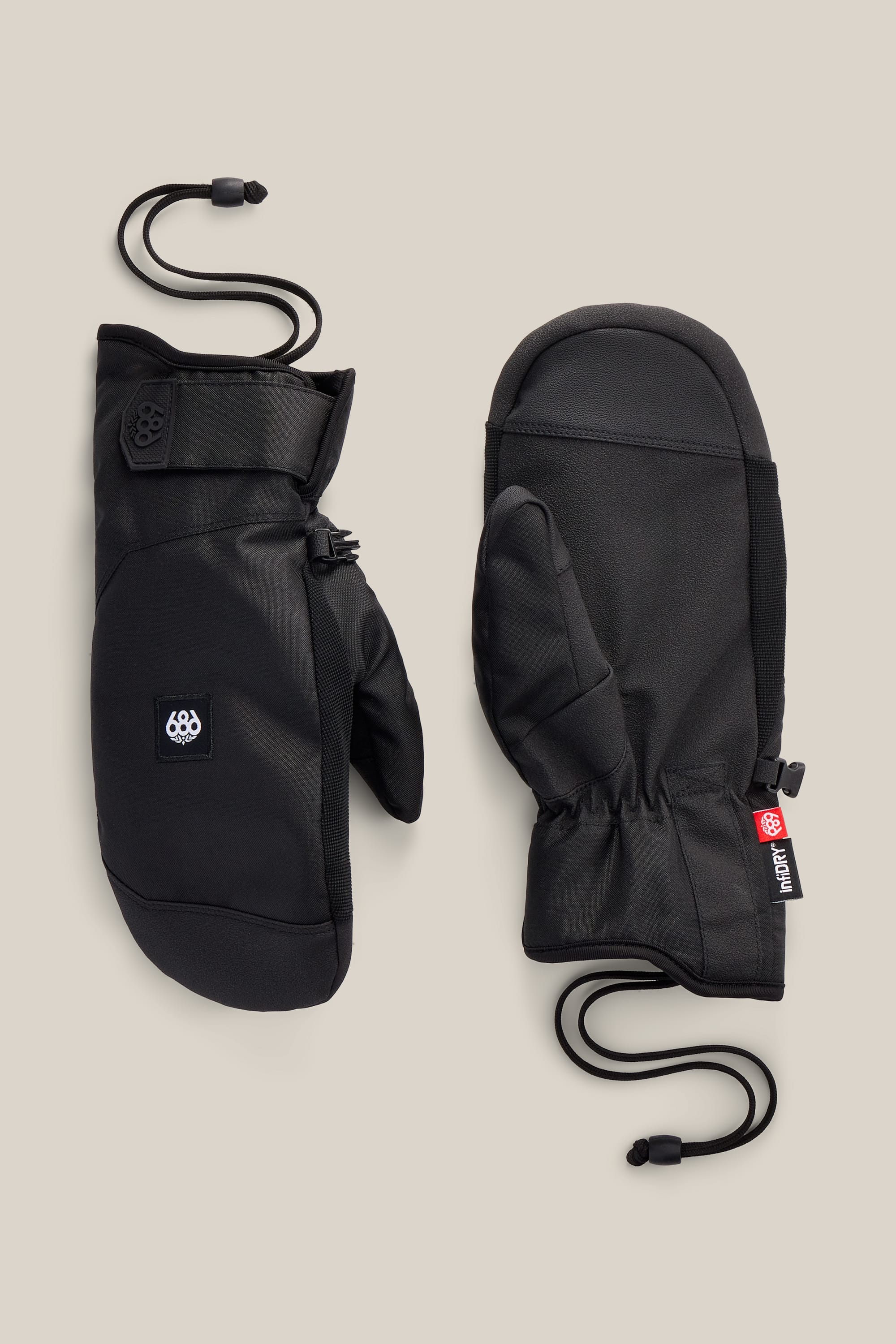 A pair of 686 Men’s Primer Mitts in black, featuring wrist straps and adjustable elastic cords, displayed palm up and palm down on a beige background.