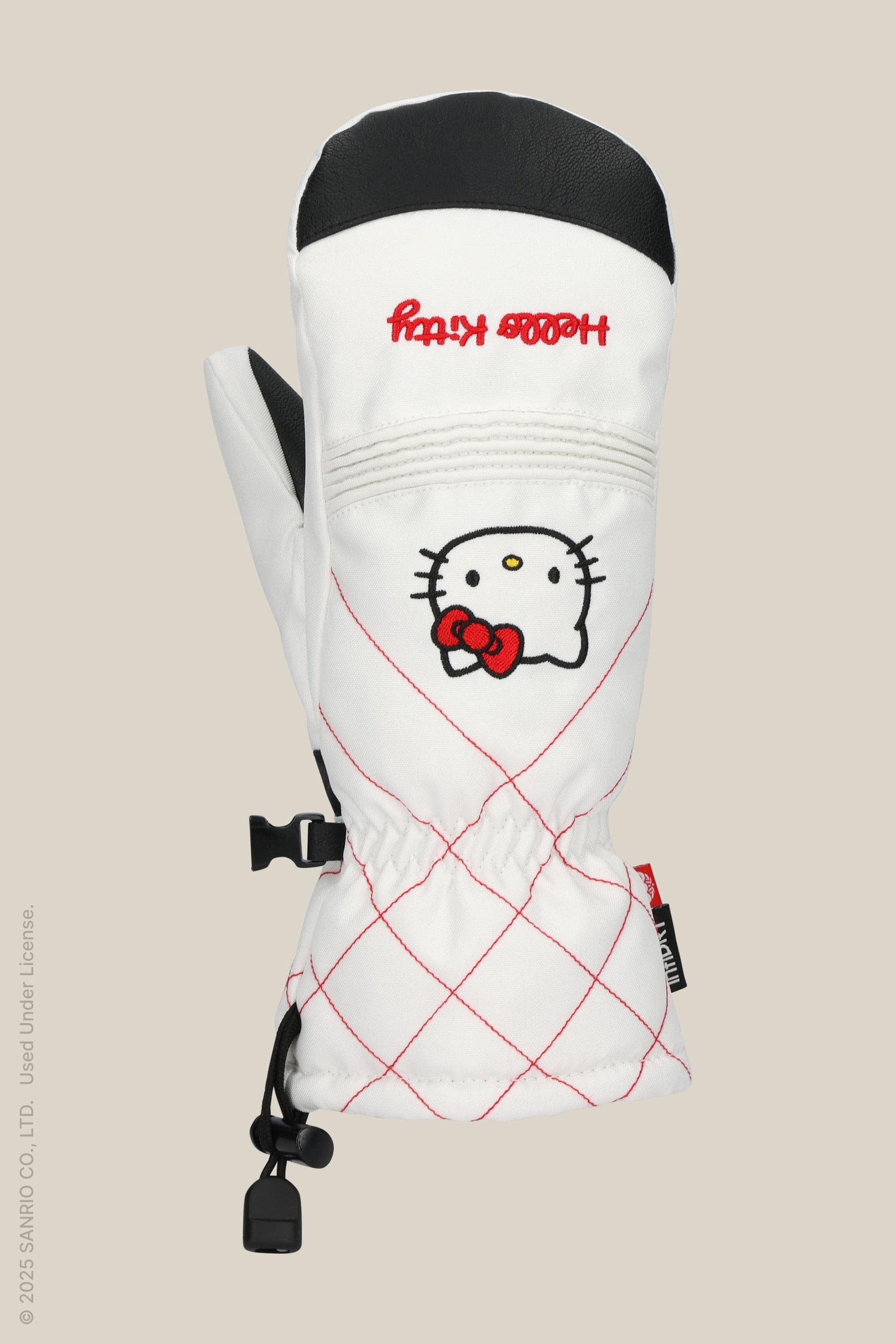 The 686 Womens Jubilee Mitt by 686 is white with a red diamond pattern, an embroidered Hello Kitty face holding a red bow, black thumb, waterproof design, light insulation for warmth, and decorative red text on the cuff.