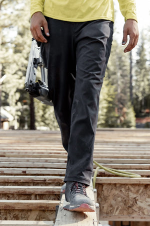 A person wearing the 686® Men's Unwork® Pant - Slim Fit by 686 walks on a wood floor.