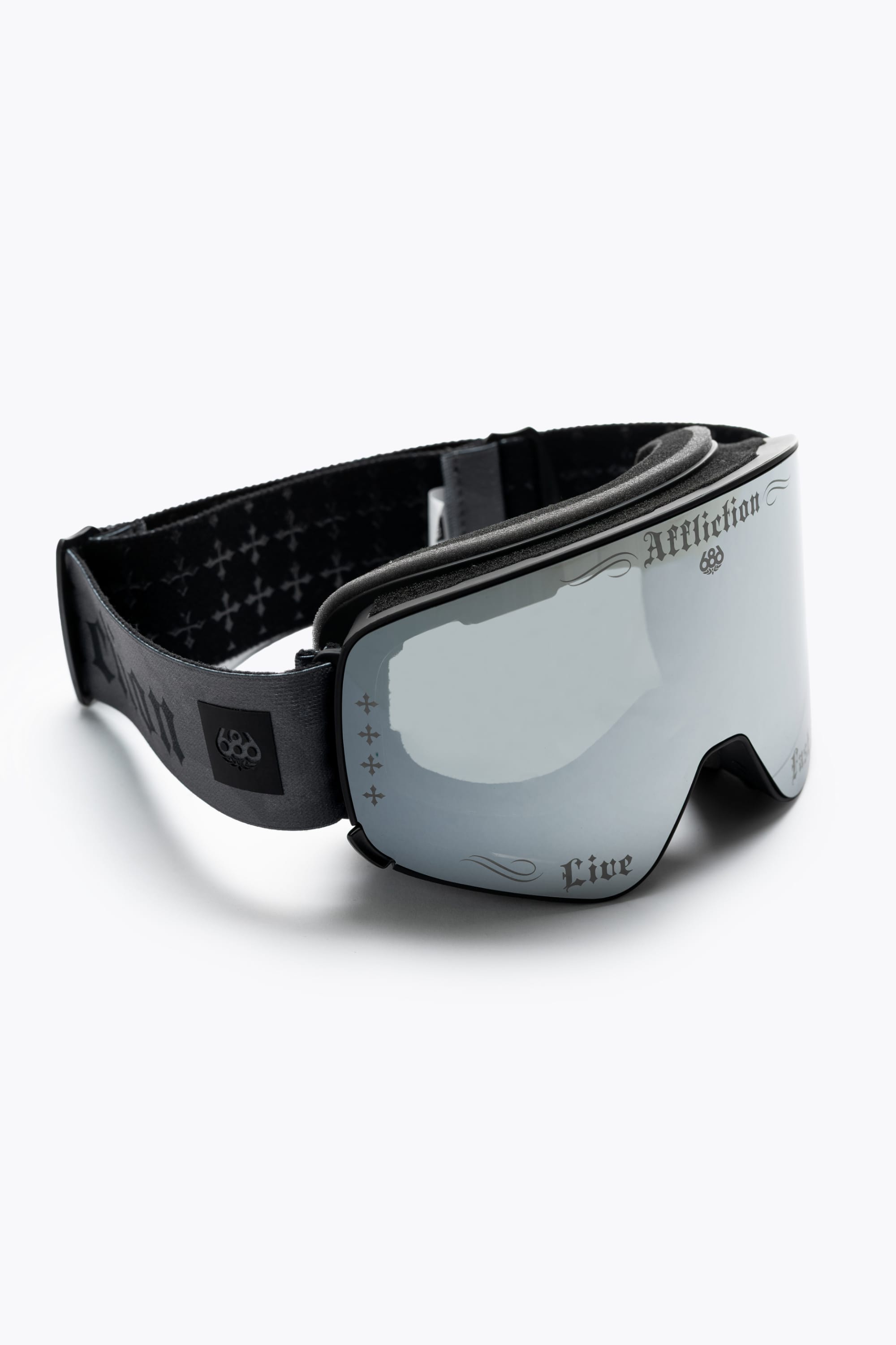 The 686 SMARTY® Magnetic Goggle by 686 features black frames, reflective lenses, “Affliction” and “Live” in stylized fonts on the frame and lens, plus a patterned adjustable strap.