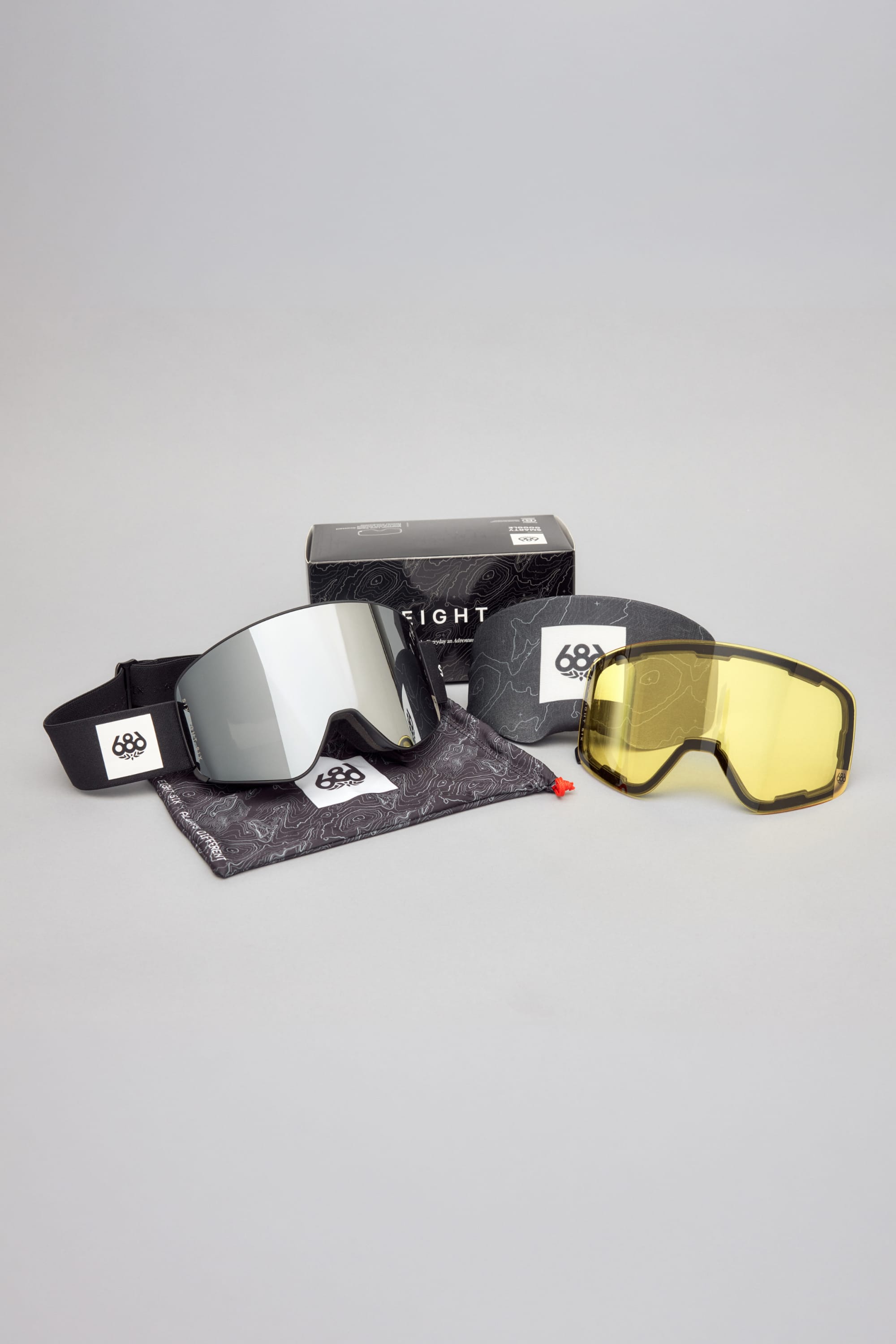The 686 SMARTY® Magnetic Goggle by 686 is shown on a gray background, featuring interchangeable lenses—a mirrored lens attached to the frame, an additional yellow lens, a carrying pouch, and a branded box.