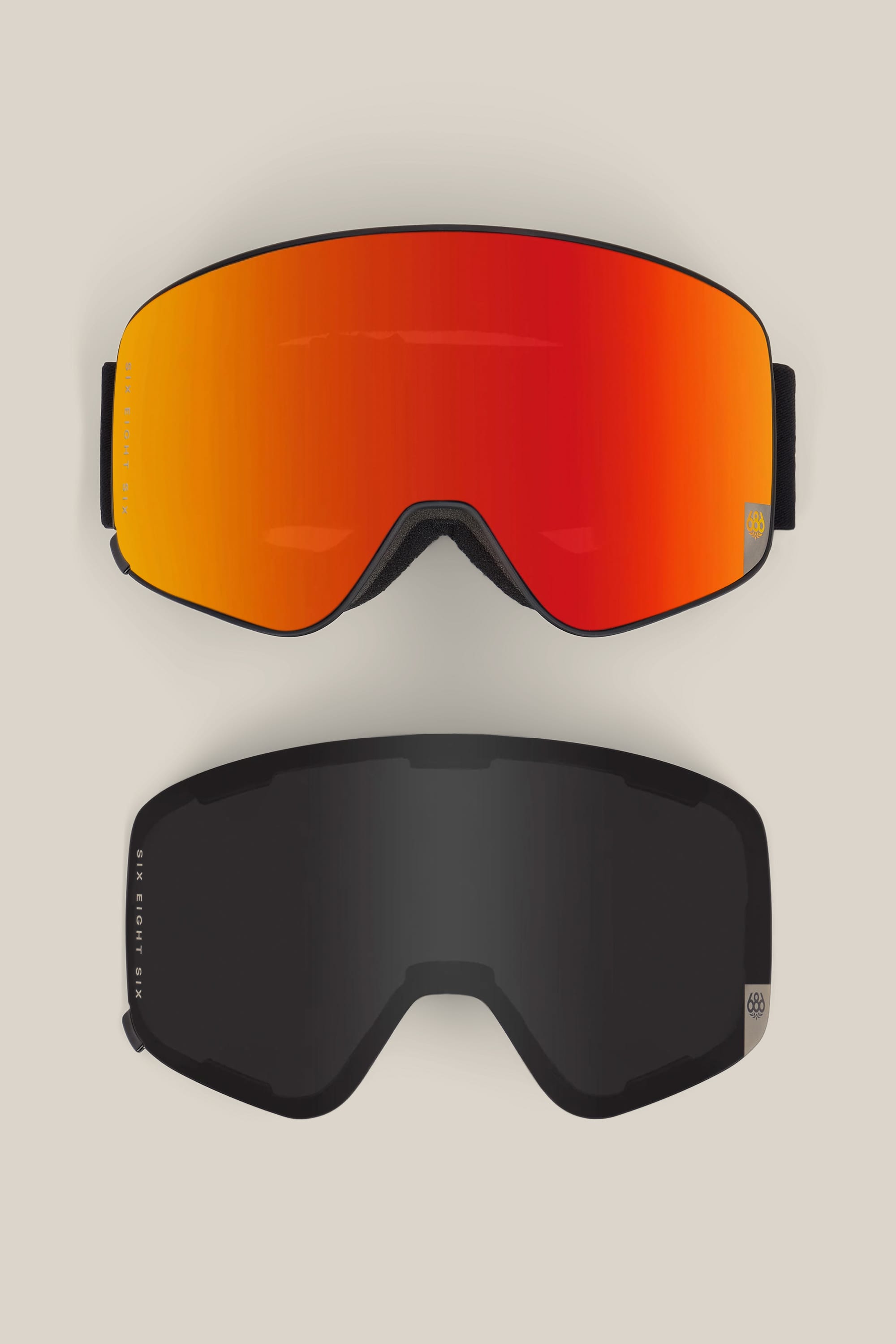 Two 686 SMARTY® Magnetic Goggles by 686 are displayed side by side on a beige background. The top goggle features a bright orange-red reflective lens, while the bottom goggle has a dark, nearly black lens. Both goggles have black frames and straps.