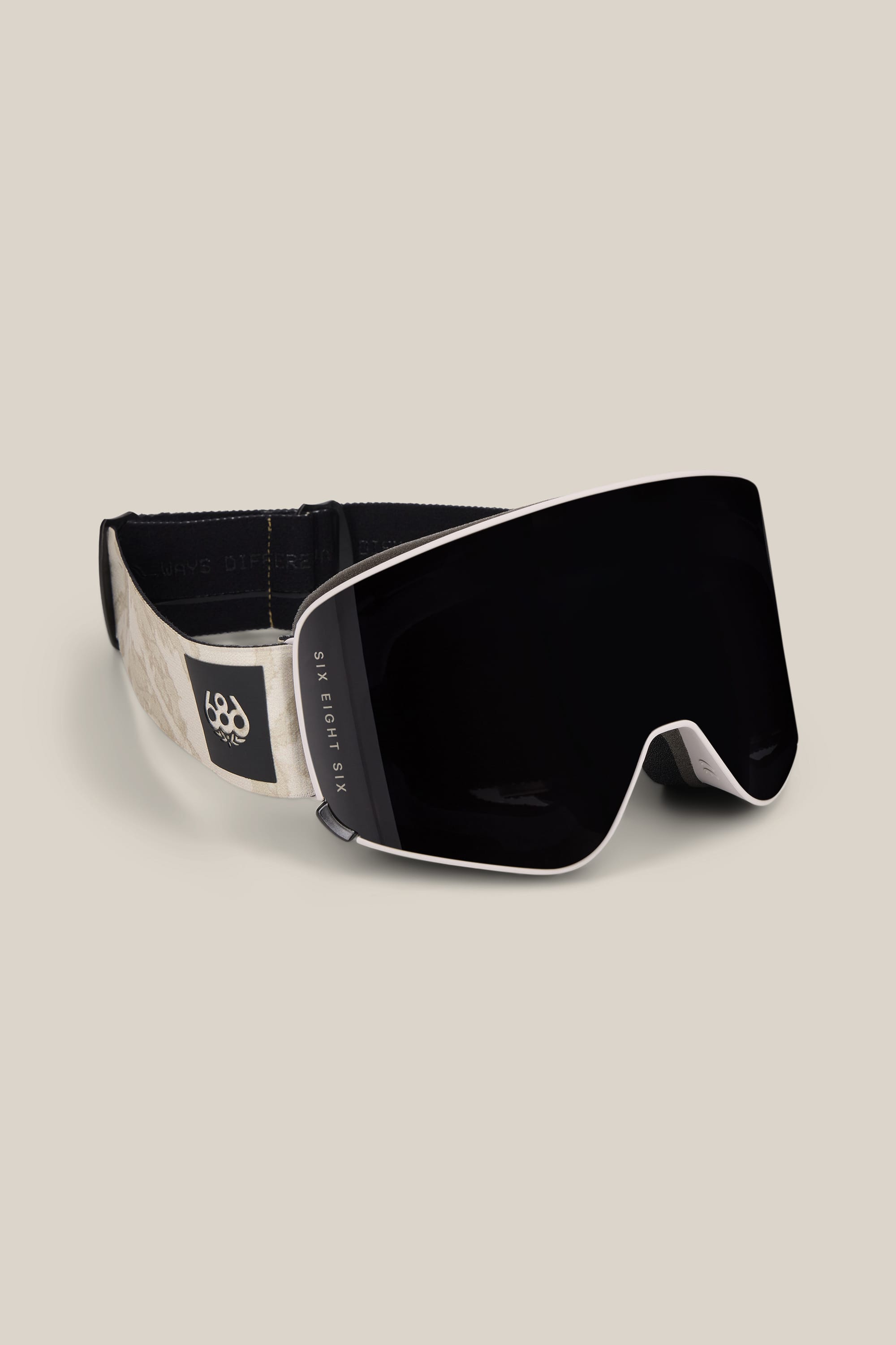 Sure! Here’s a rewritten sentence using the product data: The 686 SMARTY® Magnetic Goggle by 686 features a wide, curved black lens and a beige adjustable strap with the brand’s logo, displayed on a plain light beige background.