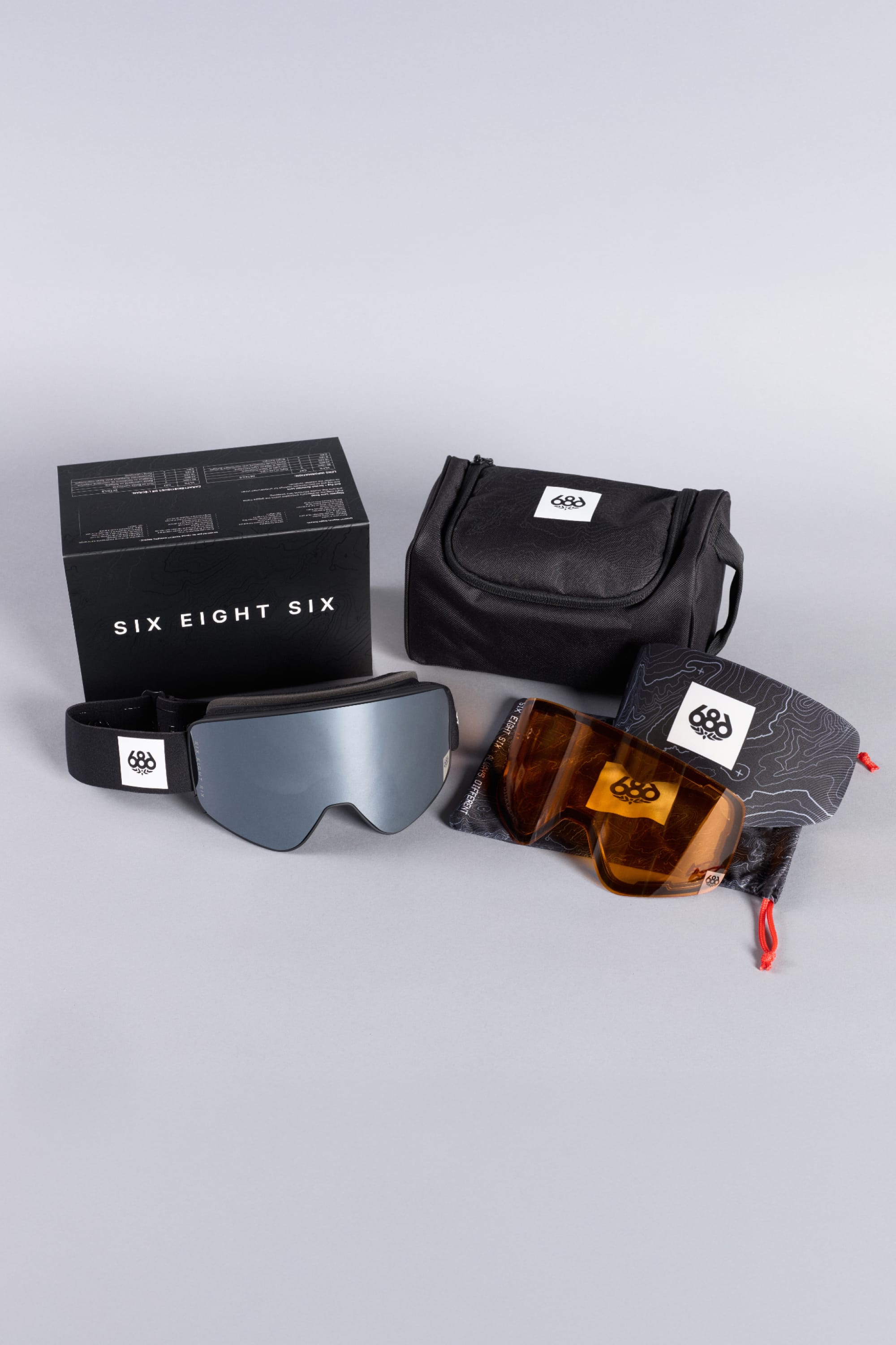 A set of 686 SMARTY® Magnetic Goggles from 686, featuring two interchangeable lenses, a black carrying pouch, and a branded box, displayed on a light gray background.