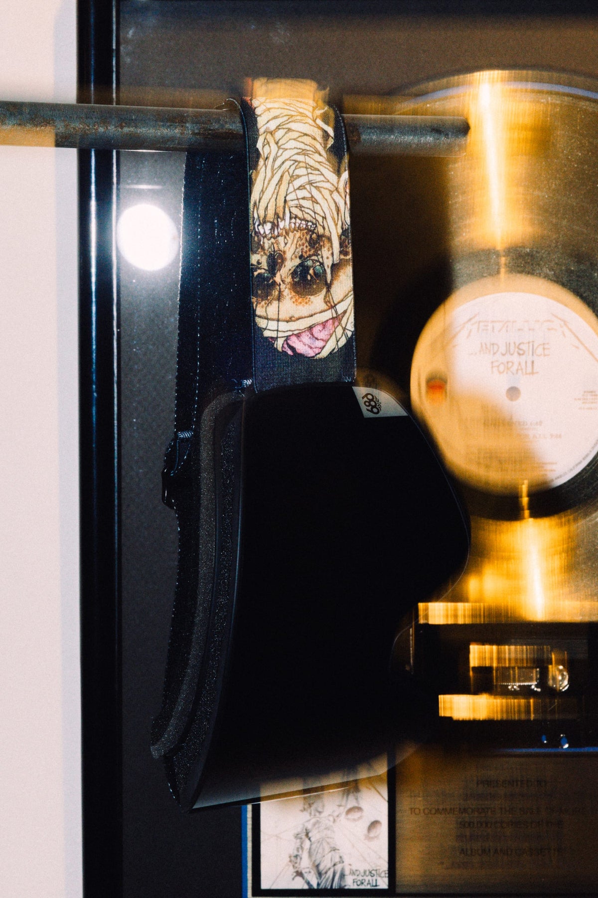 686 SMARTY® Magnetic Goggle with magnetic lenses and a graphic mummy-print strap, hanging in front of a framed Metallica And Justice for All platinum record.