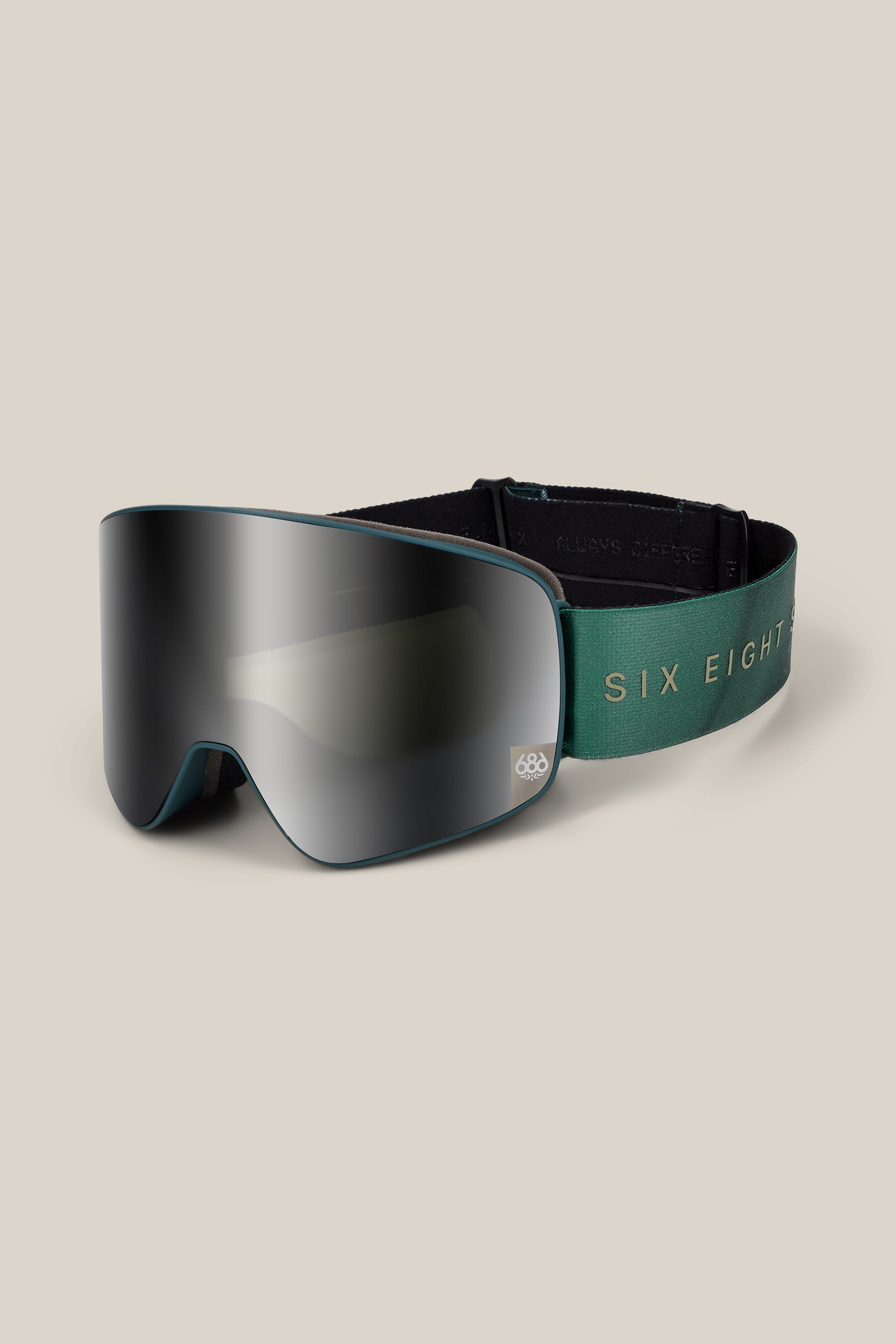 The 686 SMARTY® Magnetic Goggle by 686 features a reflective lens and a green strap with “SIX EIGHT” in gold lettering, shown against a beige background.