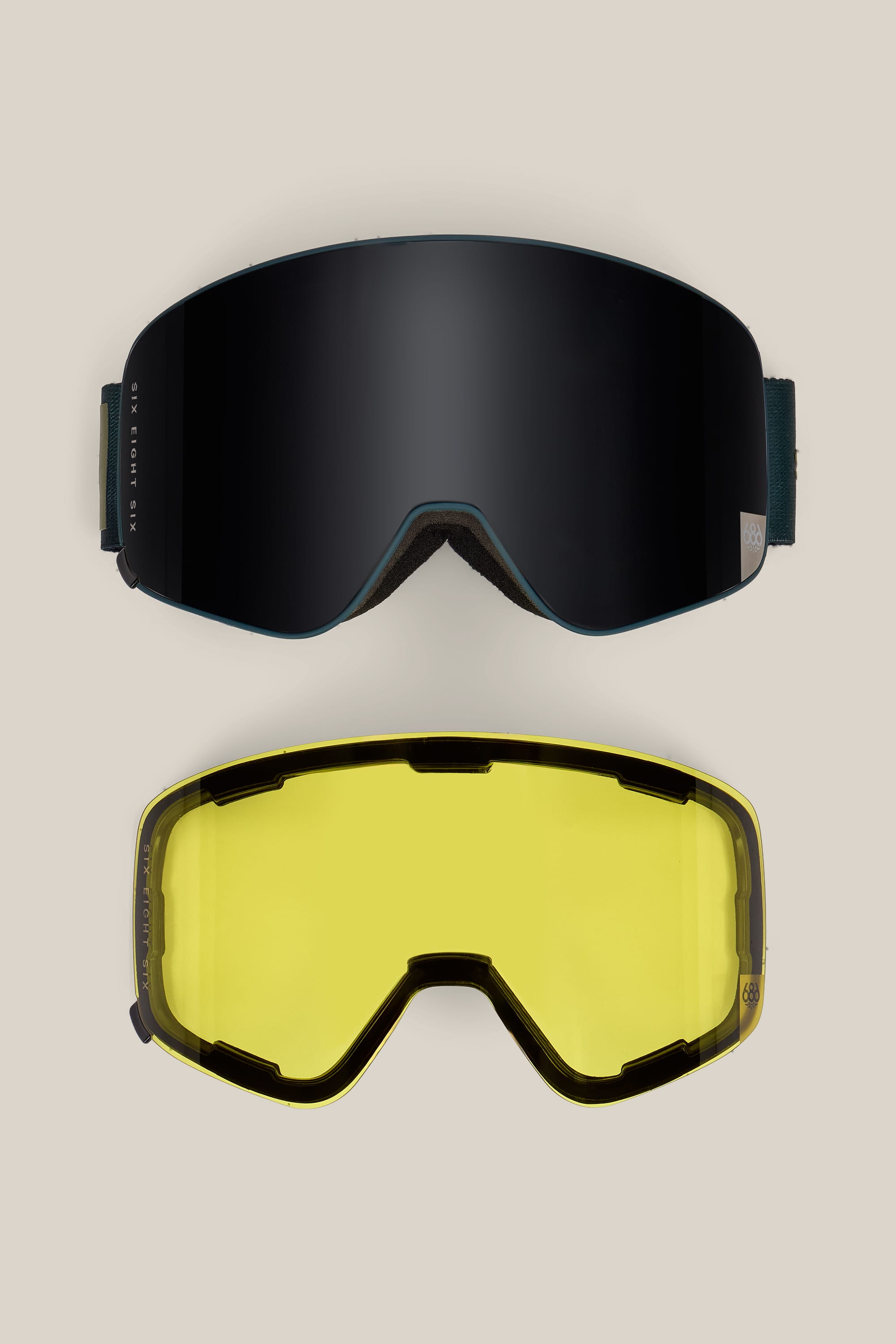 A pair of 686 SMARTY® Magnetic Goggles by 686 in black is shown above a yellow replacement lens, both displayed on a neutral background.