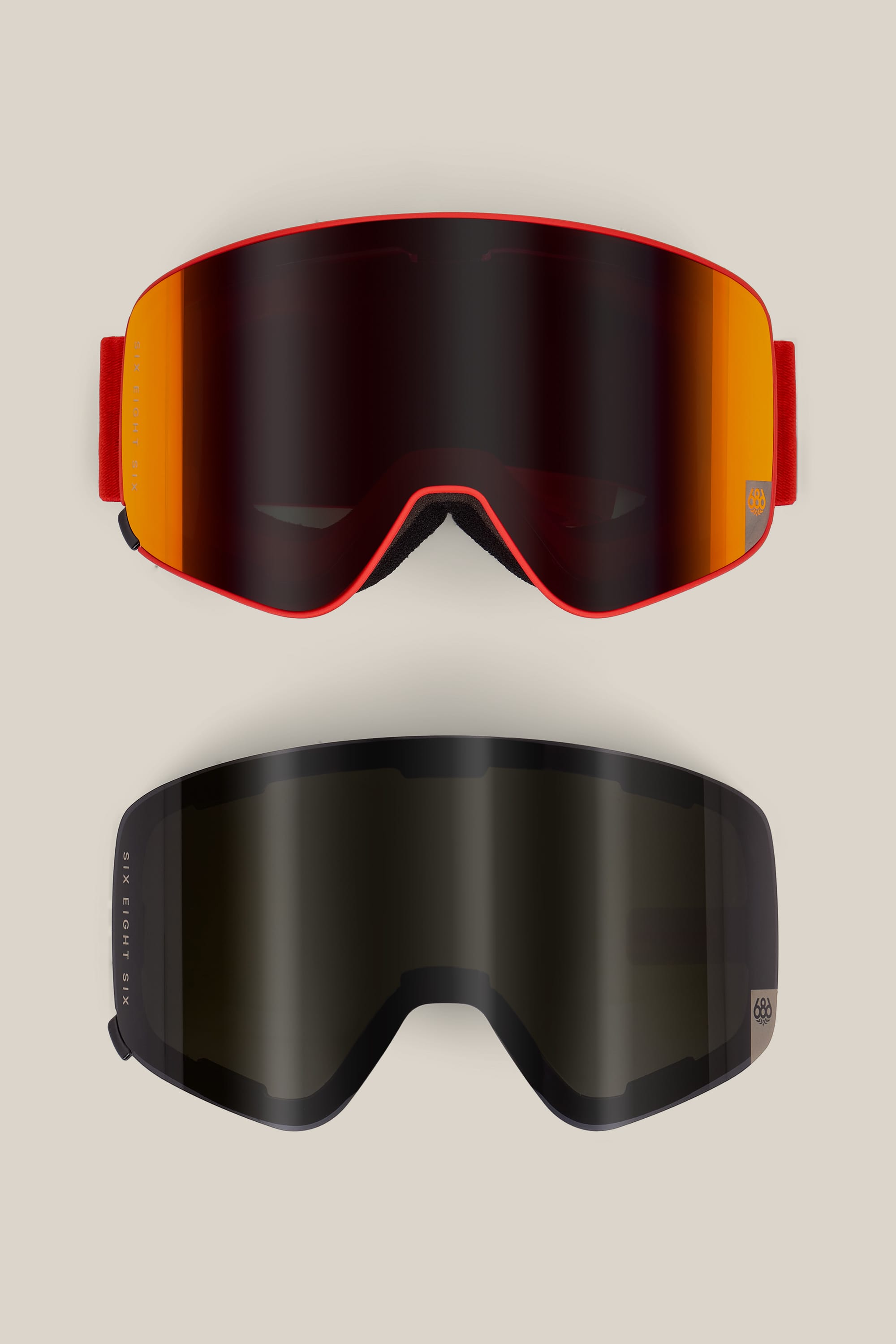 Two 686 SMARTY® Magnetic Goggles by 686 are displayed on a beige background. The top goggle features a red-orange reflective lens with a matching strap, while the bottom goggle has an almost black lens and a black strap.