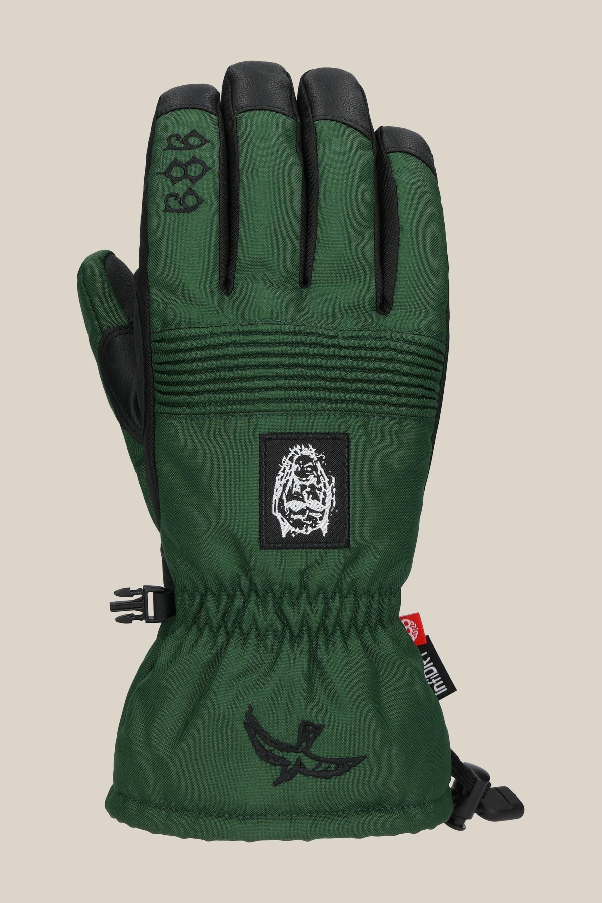The 686 Lander Glove by 686 is a green winter glove with black accents, an elastic wrist, light insulation, embroidered lion face patch, geometric shapes, bird graphic near the cuff, plus a red tag and buckle.