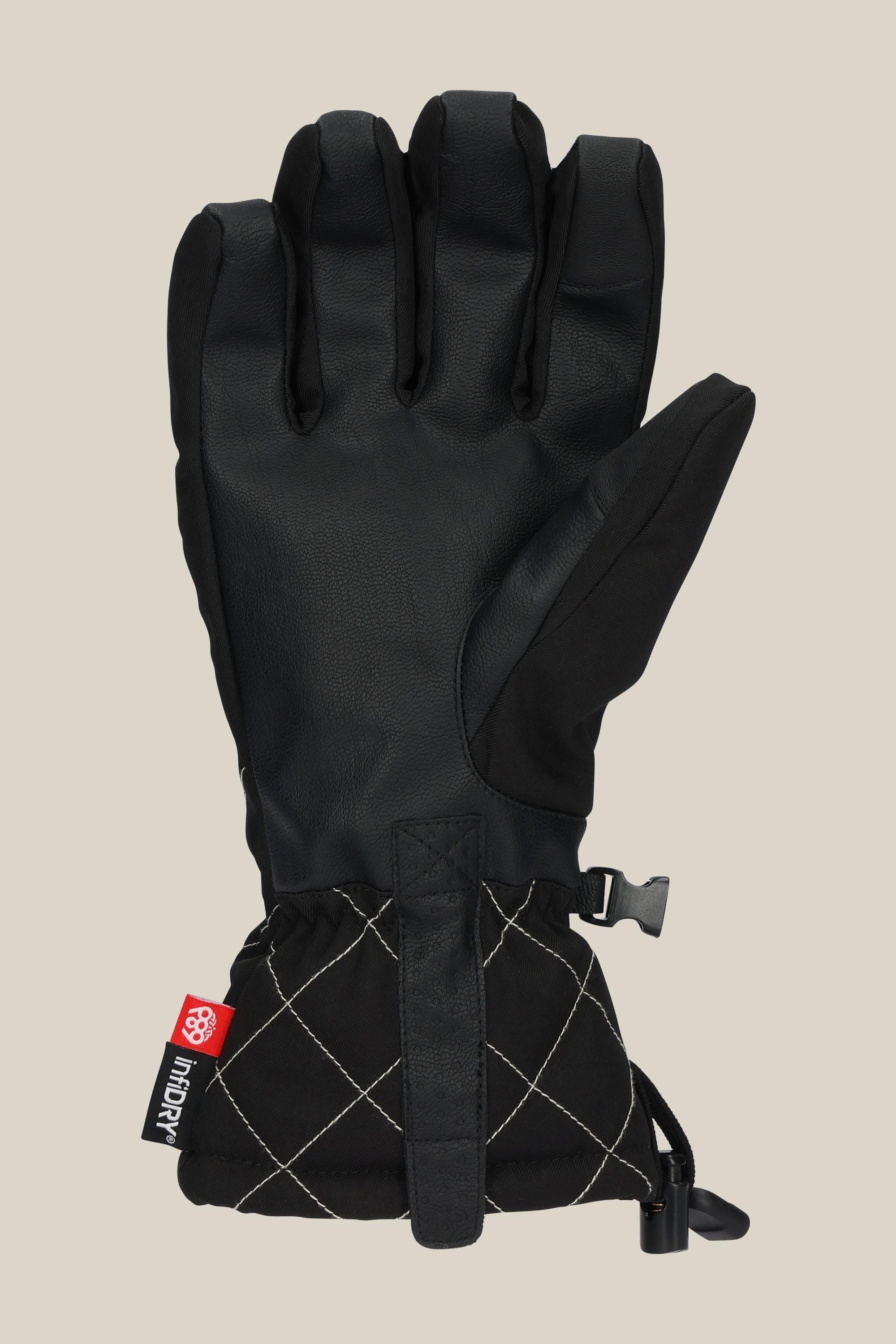 The 686 Womens Jubilee Glove is a black PU glove with a leather palm, quilted cuff, red logo tag, adjustable strap, and drawstring at the wrist, shown against a beige background.
