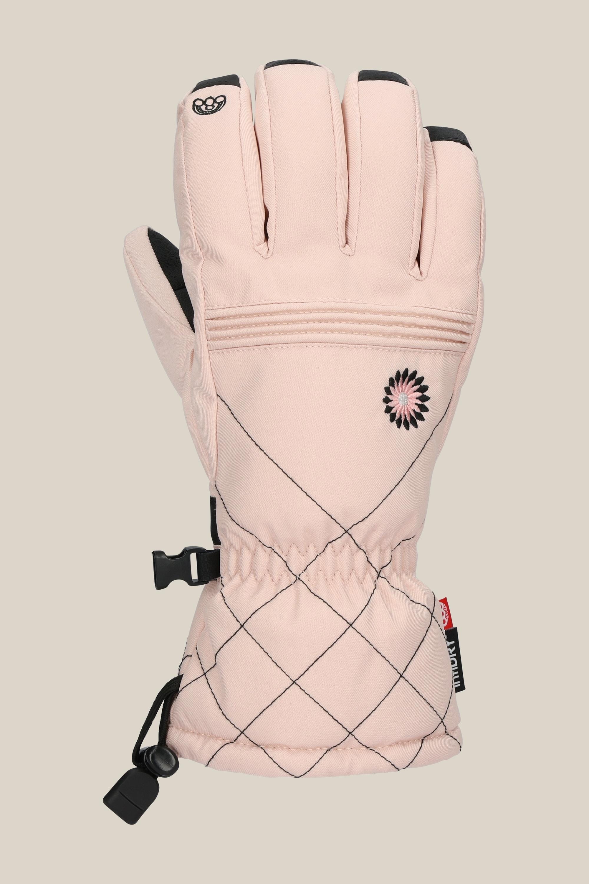 The 686 Womens Jubilee Glove by 686 is a single light pink glove with black accents, a stitched diamond-patterned cuff, small flower detail, and an adjustable wrist strap, shown on a plain beige background.
