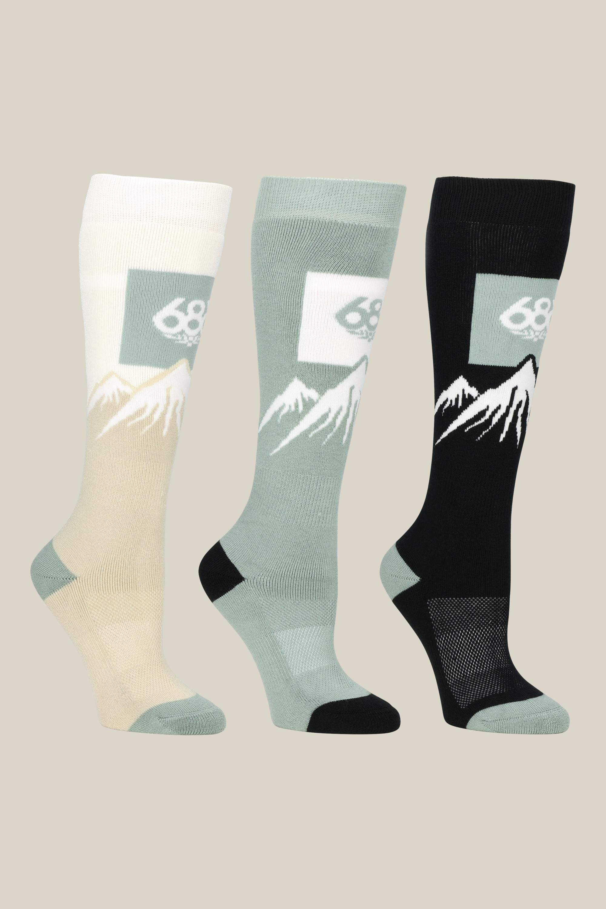 The 686 Womens Snow Caps Sock (3-Pack) includes comfy knee-high socks in beige, sage green, and black, each with a mountain graphic and the 686 logo near the top.
