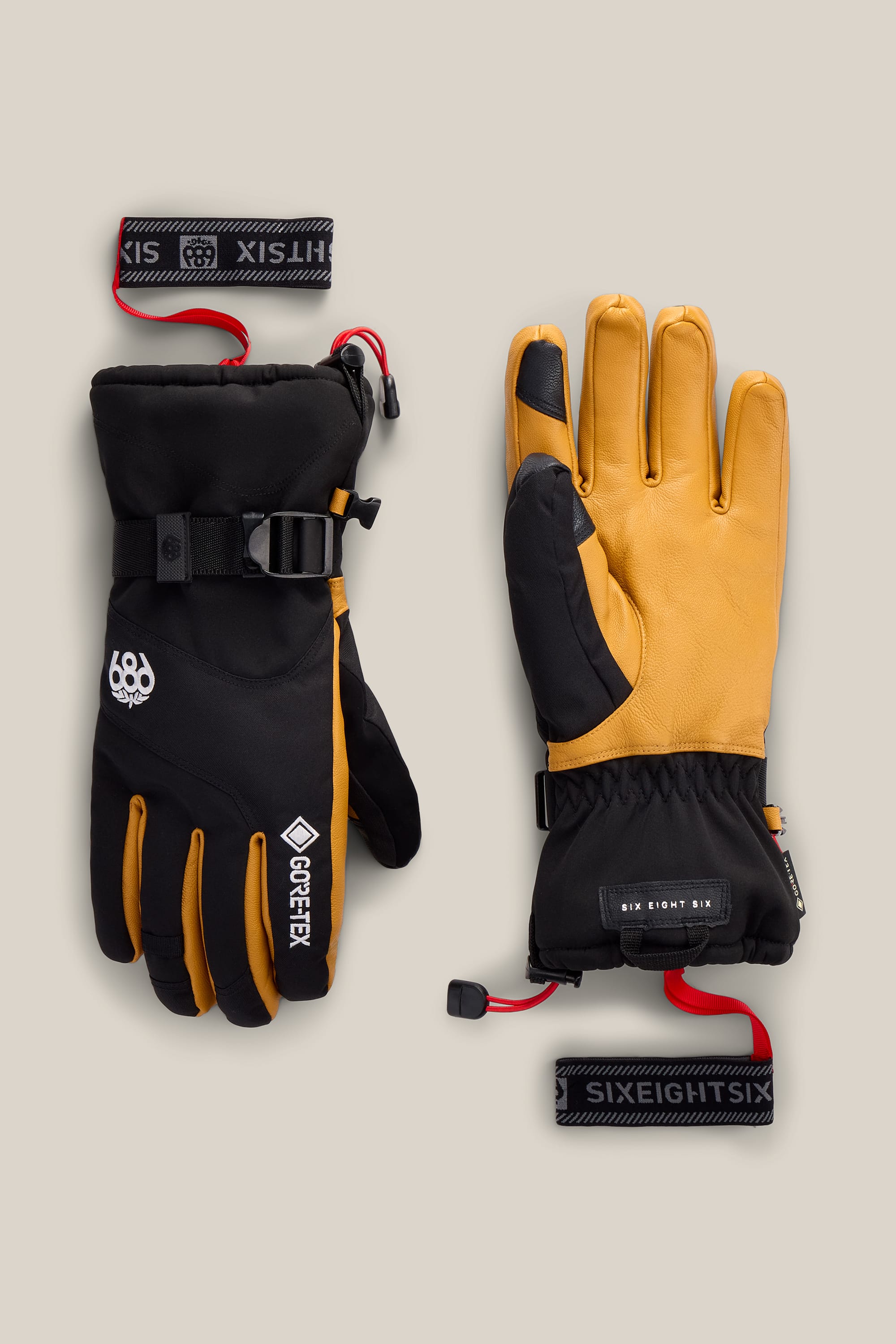 A pair of 686 Men’s GORE-TEX® Leather Linear™ Gloves in yellow and black, featuring insulated construction, wrist straps, and adjustable buckles, displayed on a beige background with one glove palm up and the other palm down.