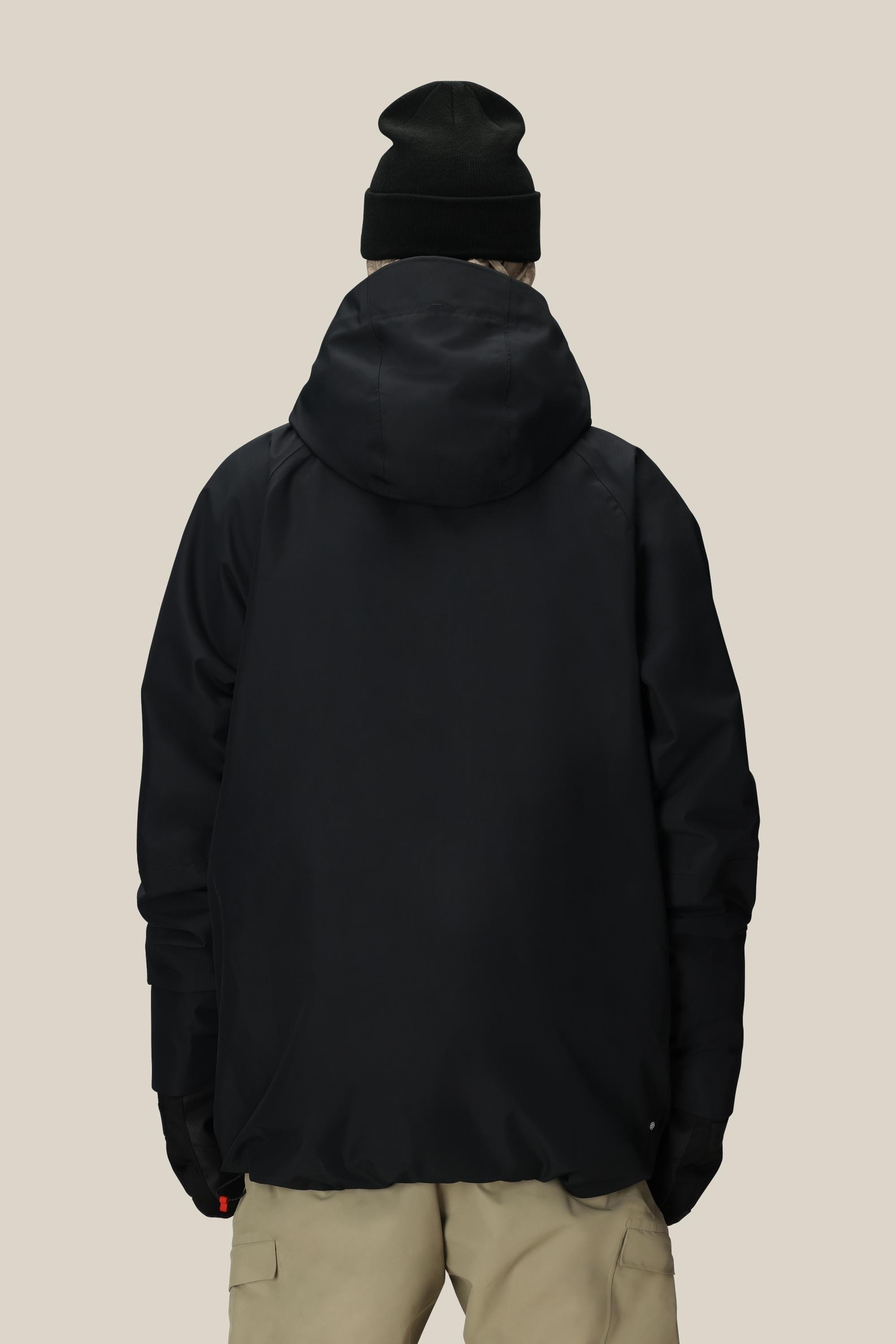A person, seen from behind against a plain light-colored background, is wearing the 686 Men’s Hydra™ Thermagraph® Jacket in black, paired with a black beanie and beige pants.