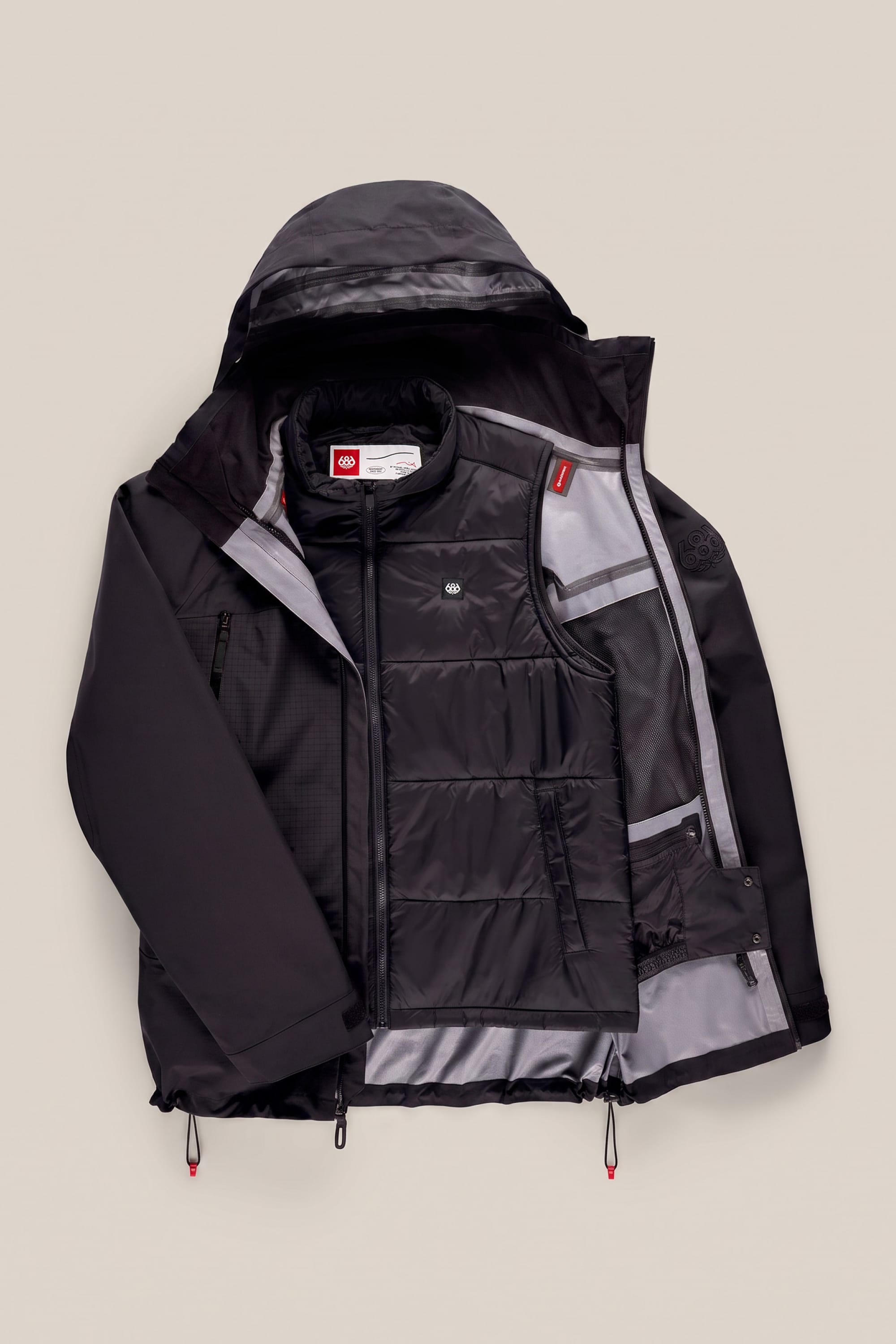 The 686 Men’s SMARTY® 3-In-1 Rodeo™ 3L Jacket by 686 is a black hooded winter jacket featuring a partially unzipped front that reveals its insulated inner lining, mesh pockets, and multiple layers designed for enhanced warmth.