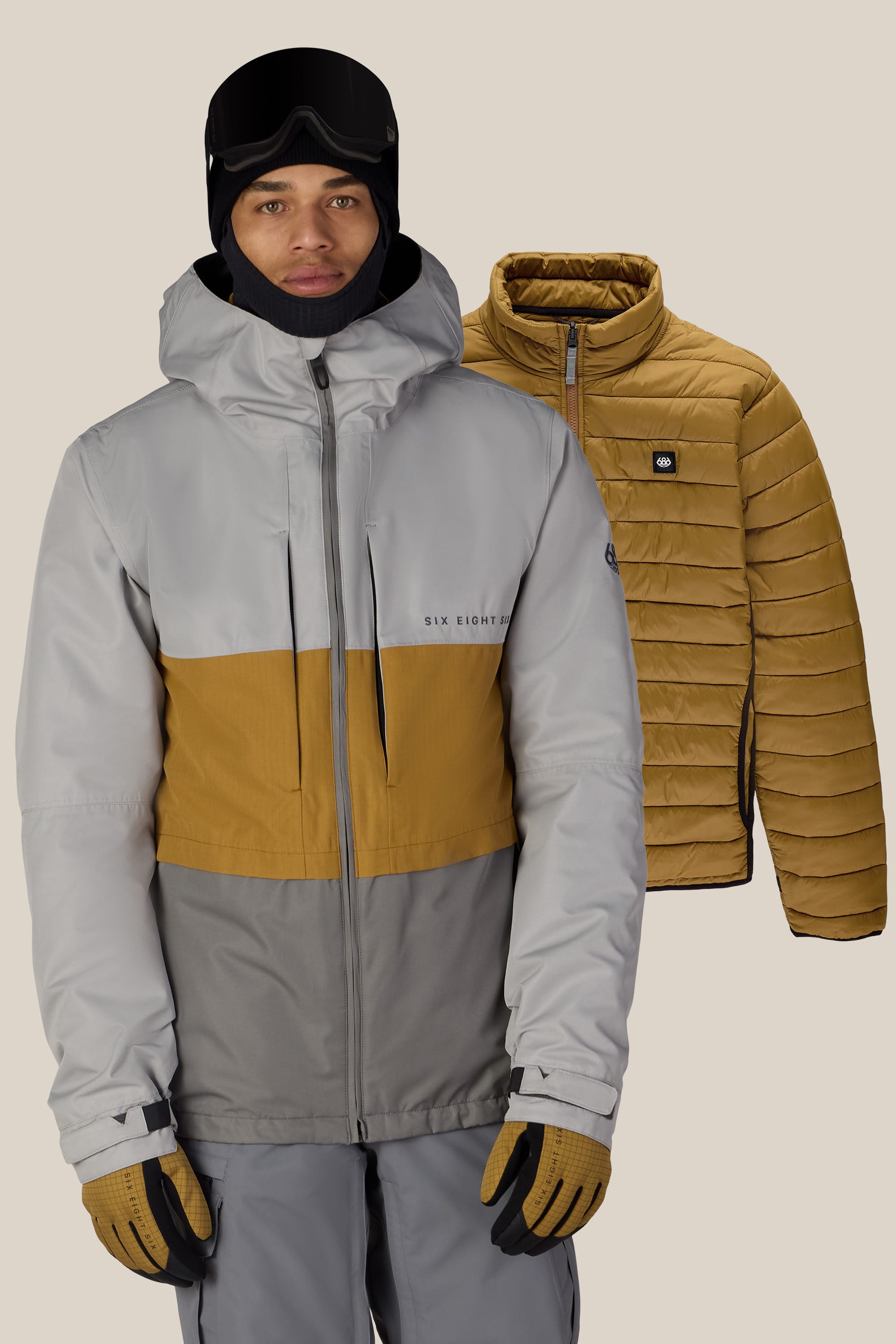 A person wearing the 686 Men’s SMARTY® 3-In-1 Form Jacket, gloves, and black ski goggles stands in front of the same jacket in tan, displayed against a solid beige background.