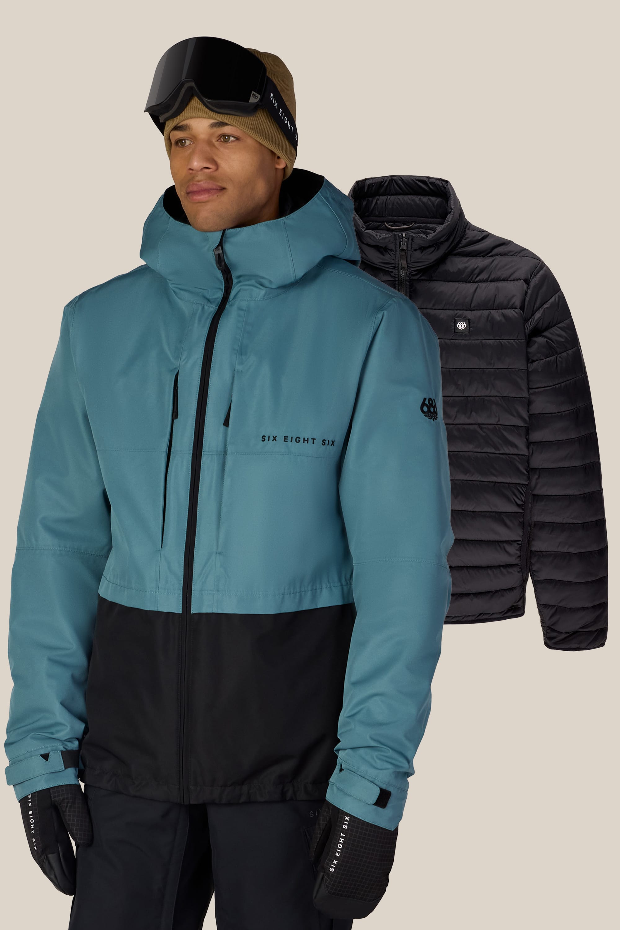 A person wearing a teal and black ski jacket, tan beanie, and ski goggles stands in front of the 686 Men’s SMARTY® 3-In-1 Form Jacket by 686, displayed on a plain background.