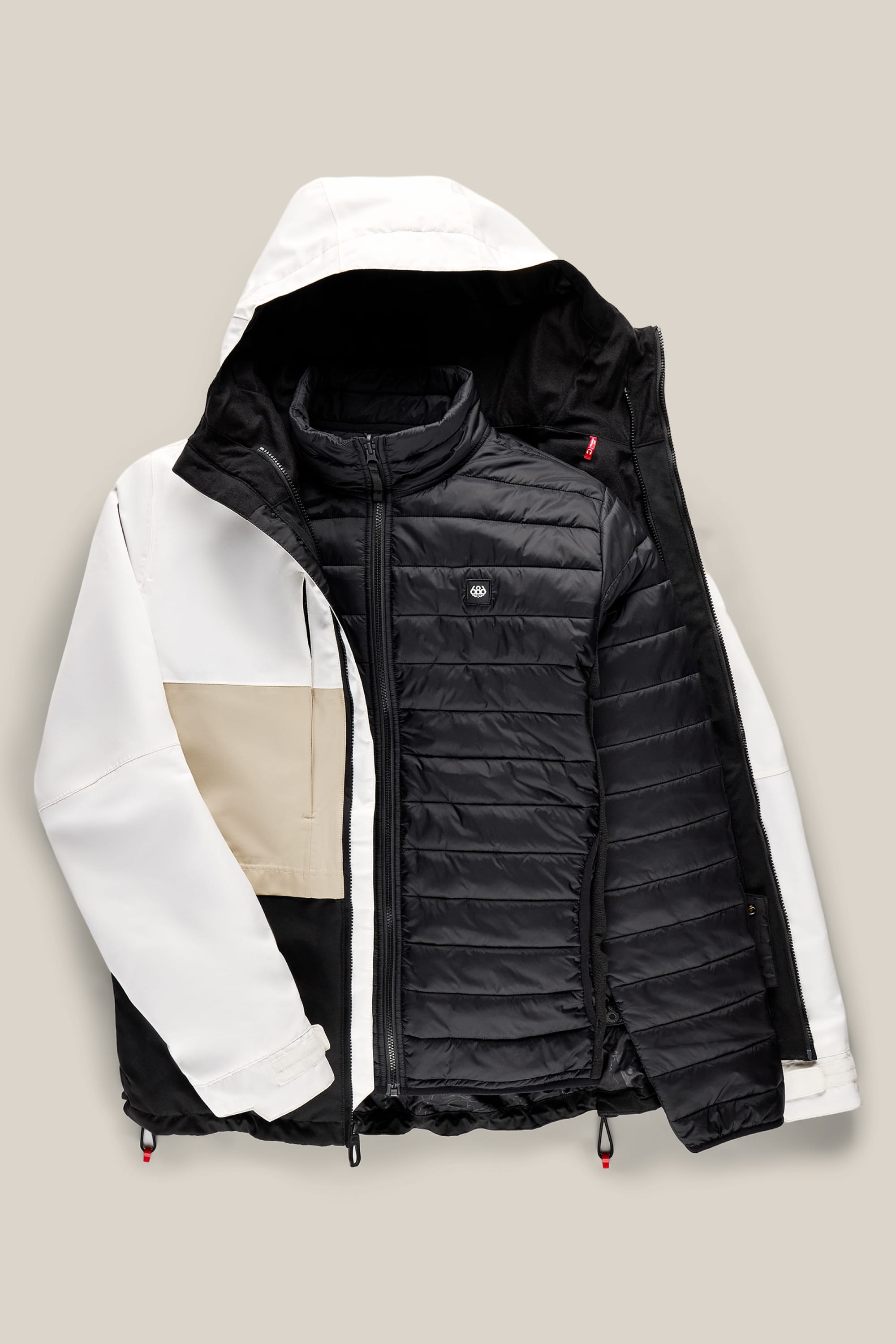 The 686 Men’s SMARTY® 3-In-1 Form Jacket by 686 is shown laid flat on a light beige background, featuring a white, beige, and black outer shell with a removable black puffer inner jacket.