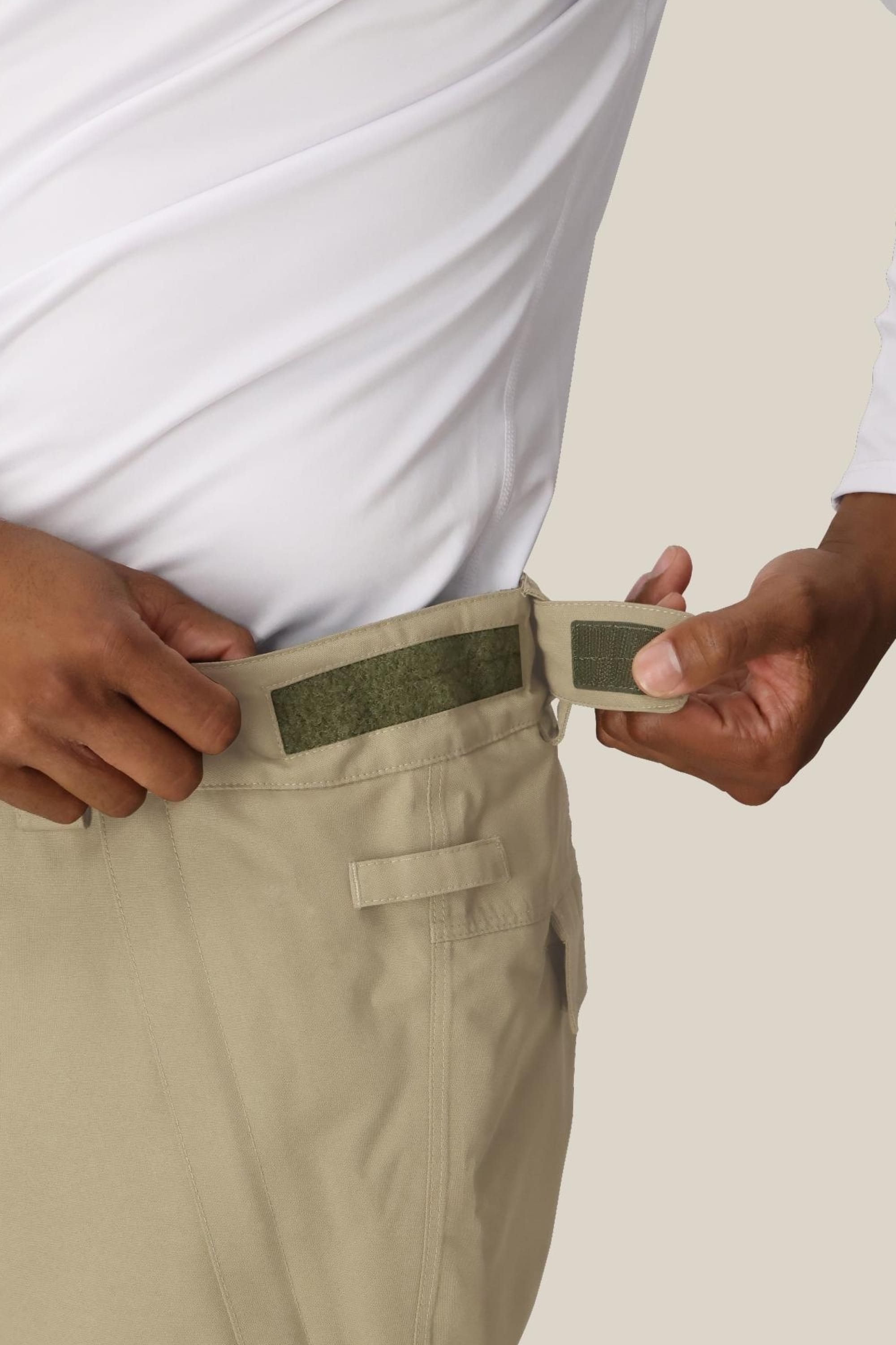 A person wearing a white shirt adjusts the side Velcro strap on 686 Mens Infinity Insulated Cargo Pant by 686.