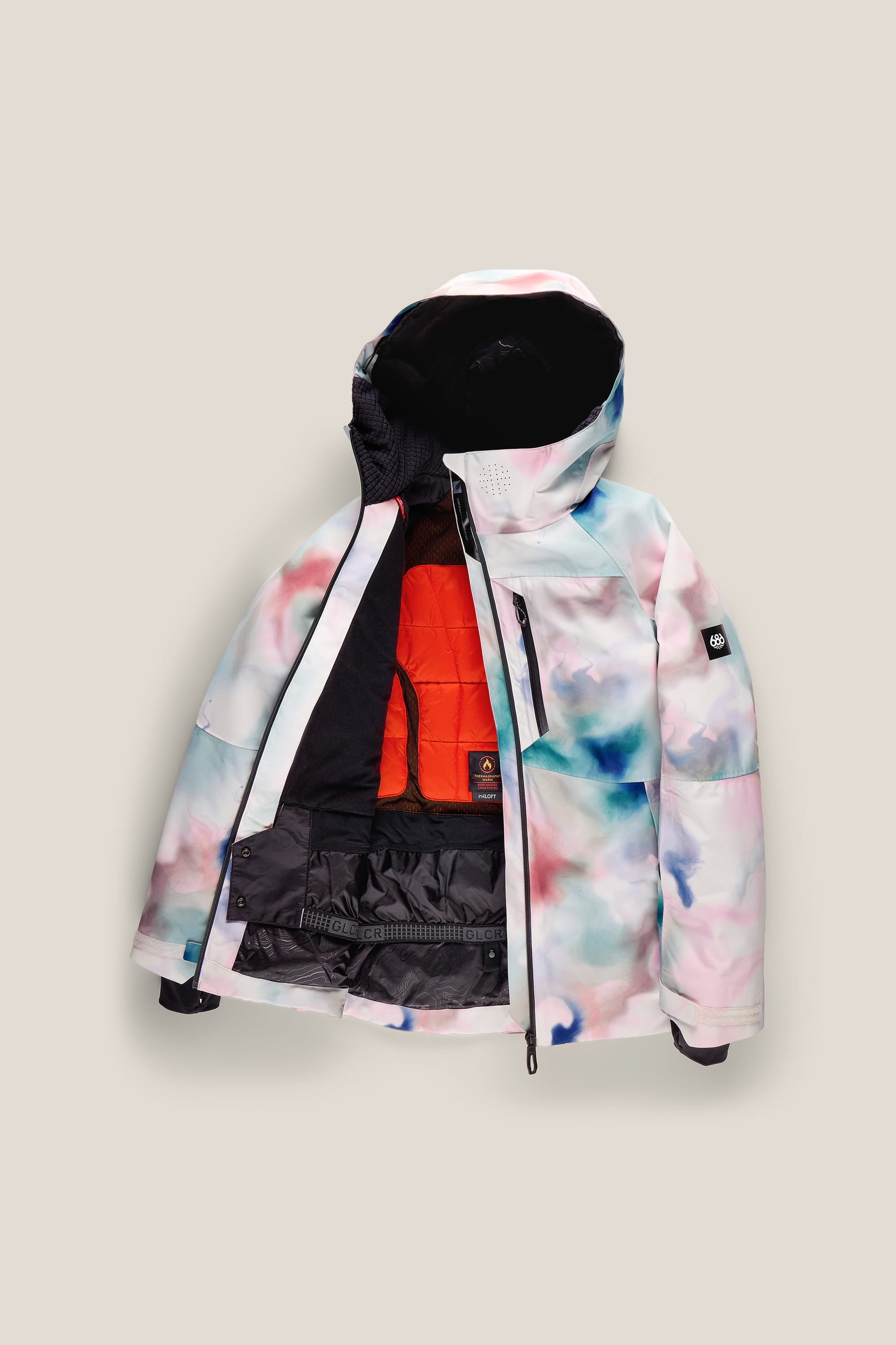 The 686 Women’s Hydra™ Thermagraph® Jacket by 686, featuring a pastel watercolor pattern and unzipped to showcase its orange quilted lining and black inner details, is displayed against a light beige background.